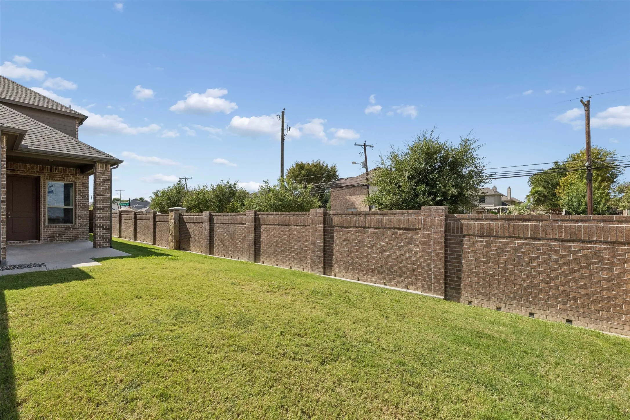 Back patio featuring no neighbors to the right or to the left, a stone and brick wall fence, wood fence and a concrete path out to the driveway.