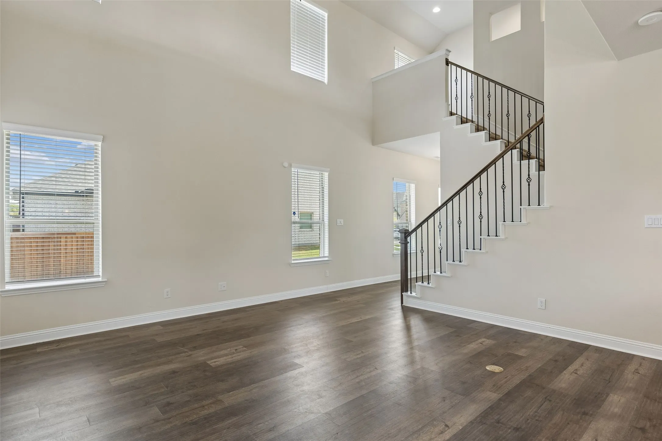 View of end of foyer and the entrance to the living room. Featuring LVP flooring, the brass outlet in the living room floor and plenty of natural light.