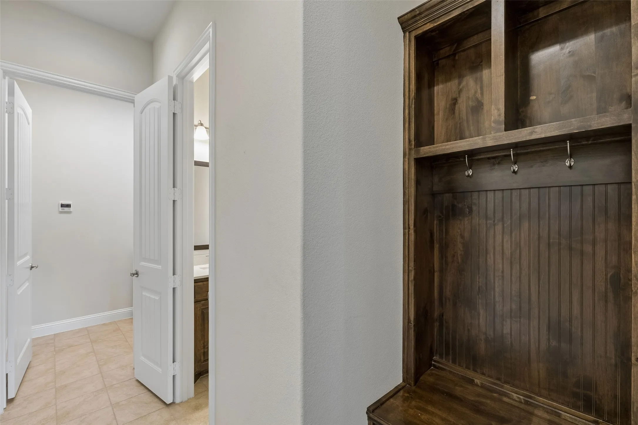 Immediately from the garage door you will find the mud room, then the 1/2 bath and last the laundry room. Hallway features the built in cabinetry and tile flooring.