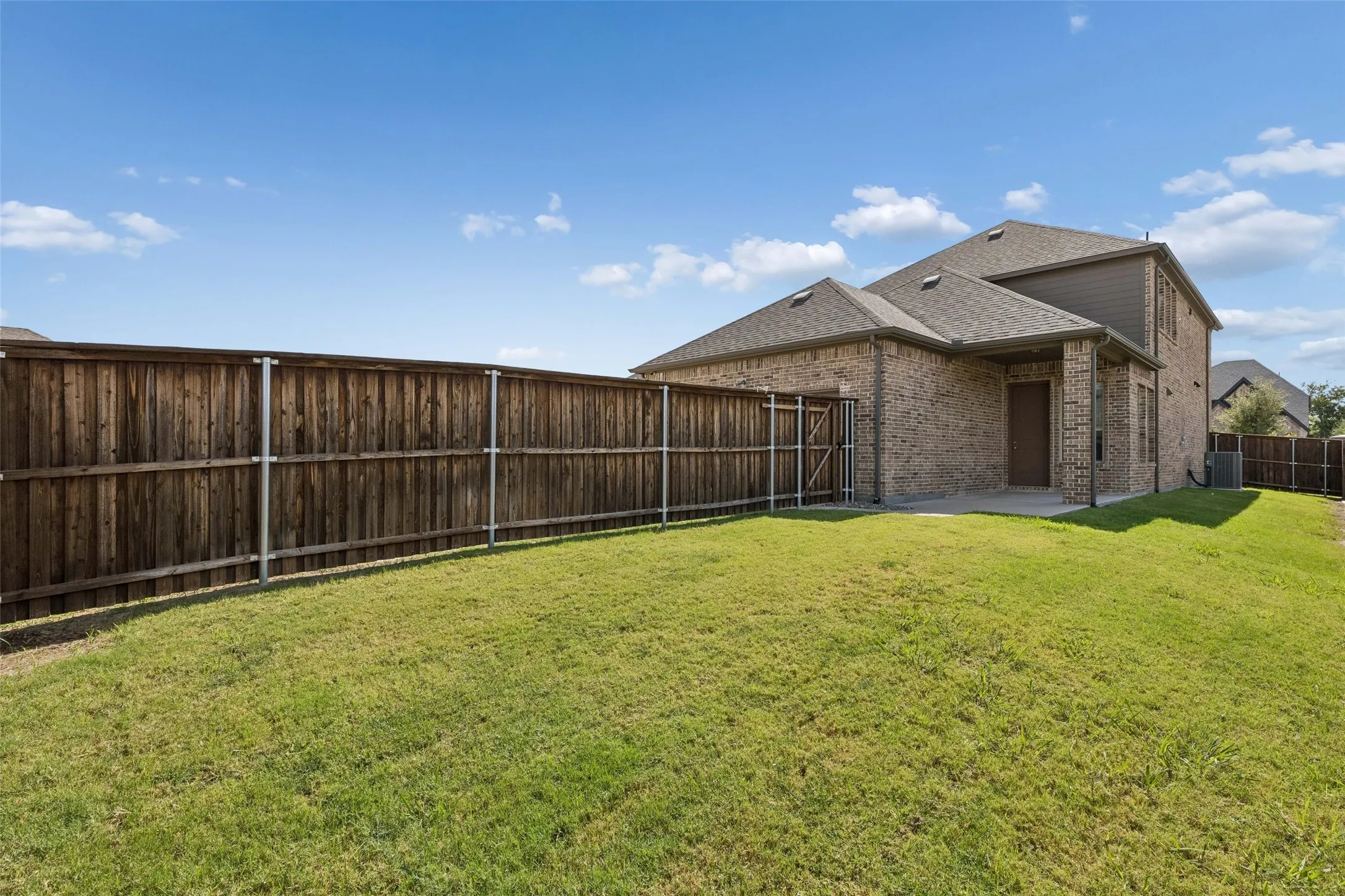 Back patio featuring no neighbors to the right or to the left, a stone and brick wall fence, wood fence and a concrete path out to the driveway.