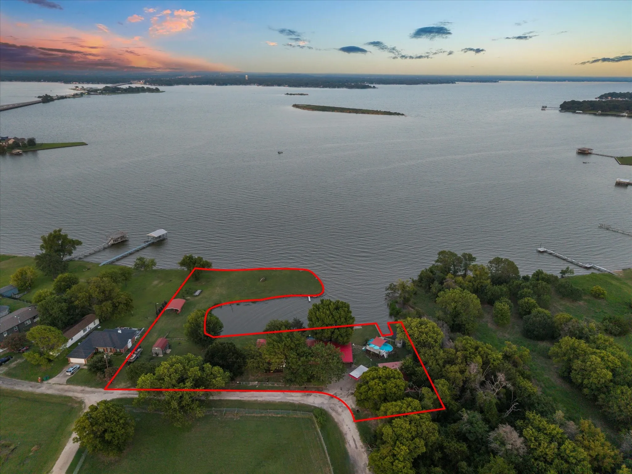 Expansive waterfront property featuring a private boat dock, dedicated pond, mature trees, a swimming pool, and a paved drive
