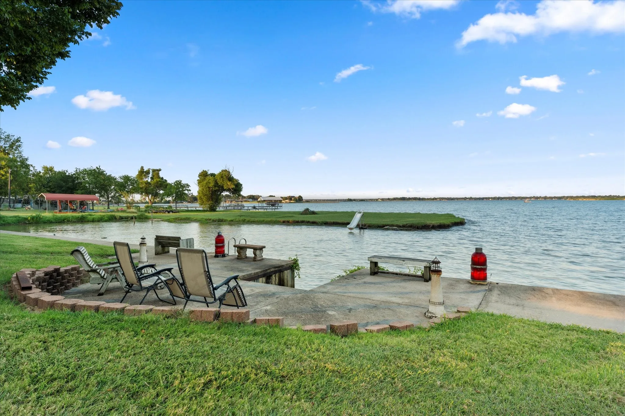 Waterside patio with concrete surface, brick-lined fire pit, and expansive waterfront access