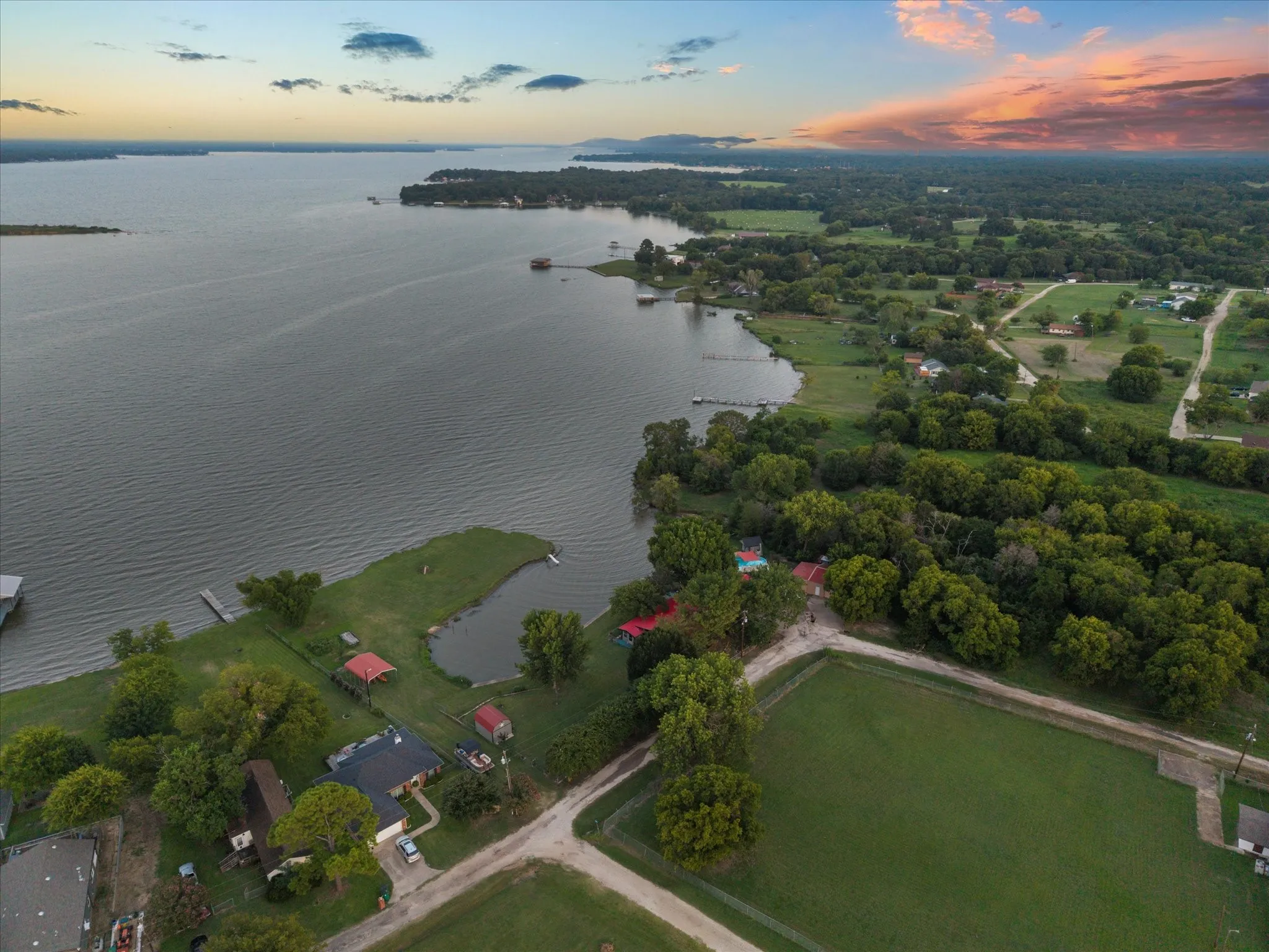 Expansive lakefront property featuring a private dock, lush green landscaping, and mature trees