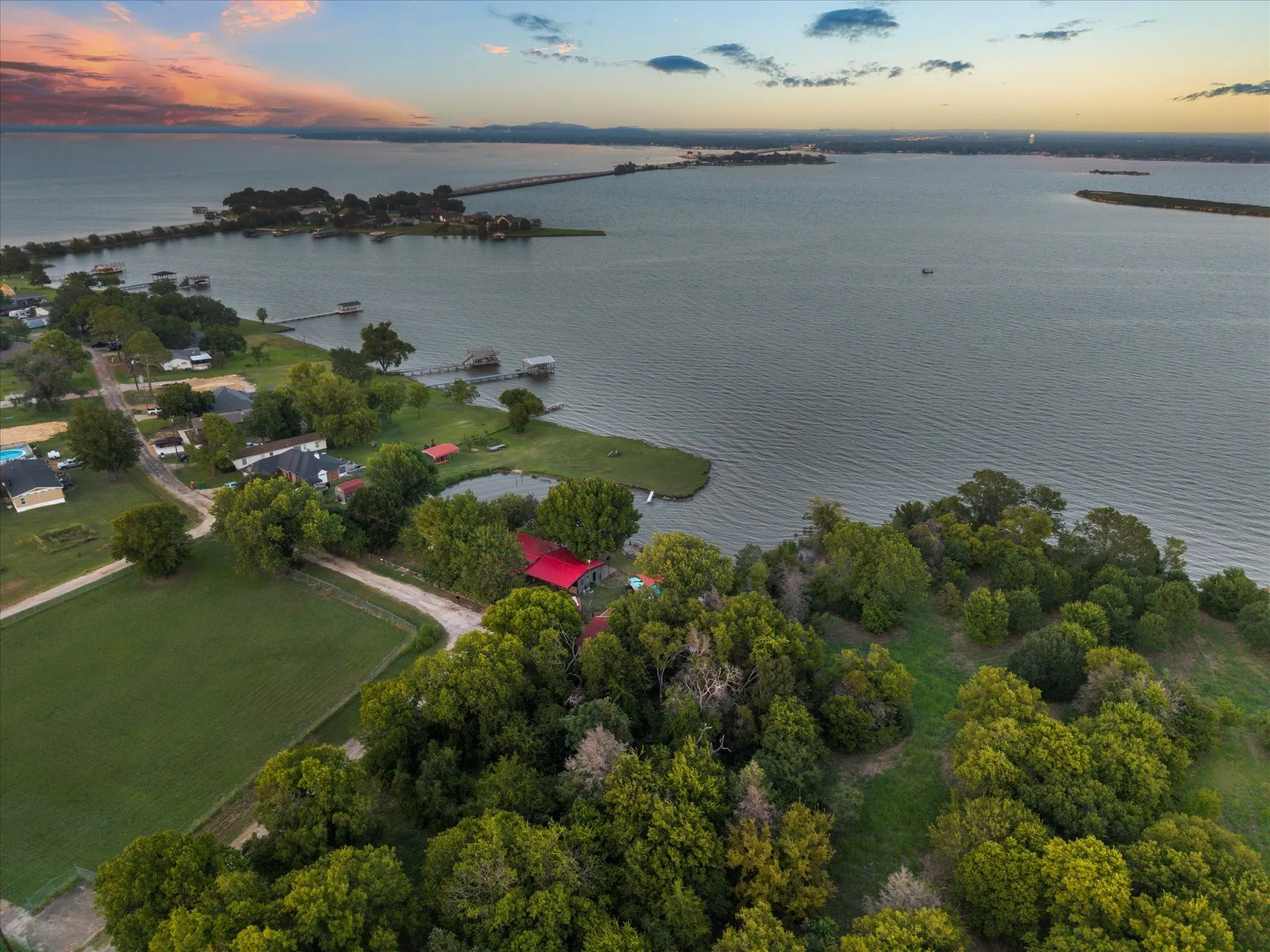 Expansive waterfront property featuring a substantial body of water, green spaces, and mature trees