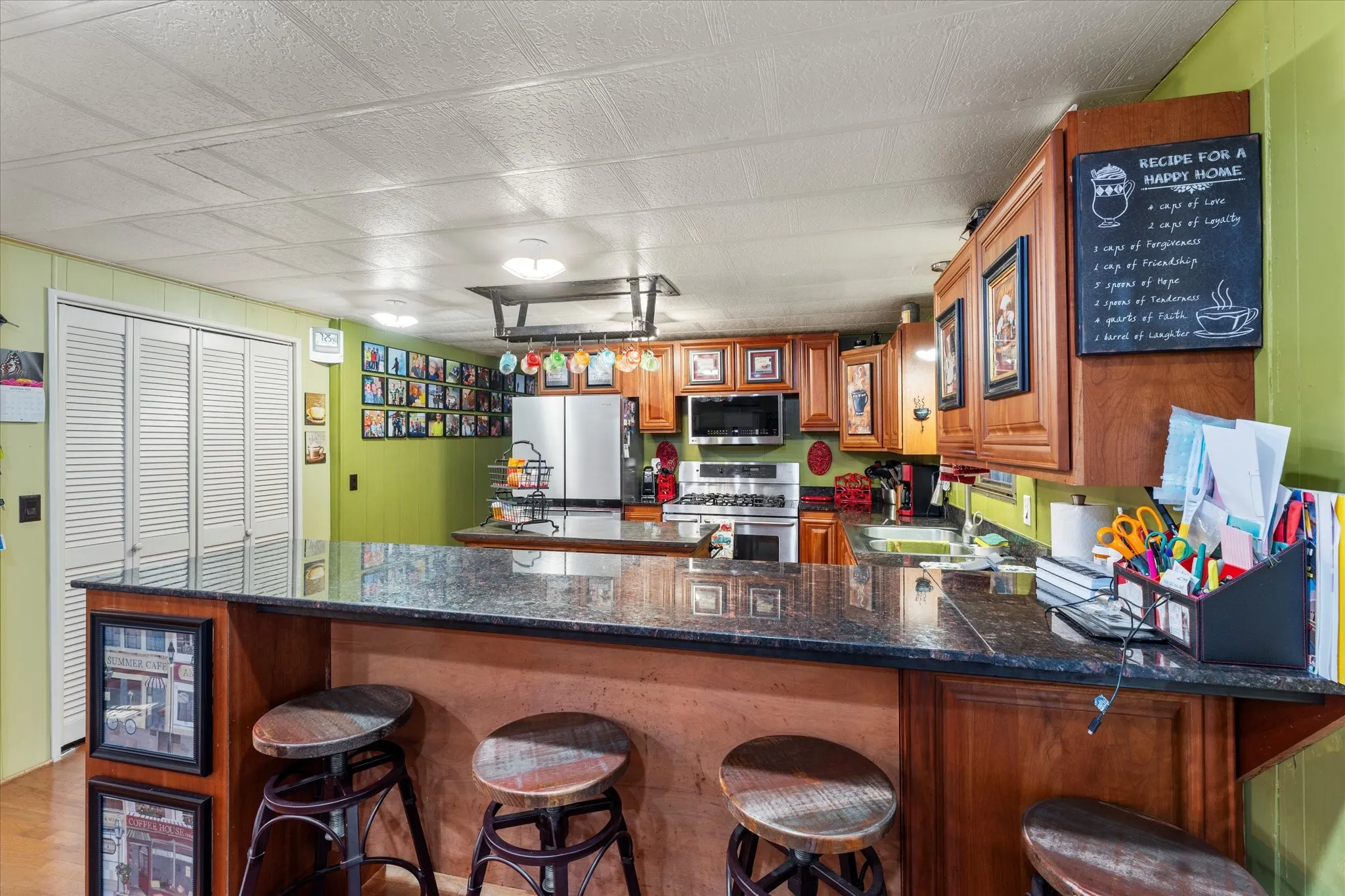 Kitchen featuring a breakfast bar with dark countertops, wood-finish cabinetry, built-in stainless steel appliances, and a wall-mounted pot rack