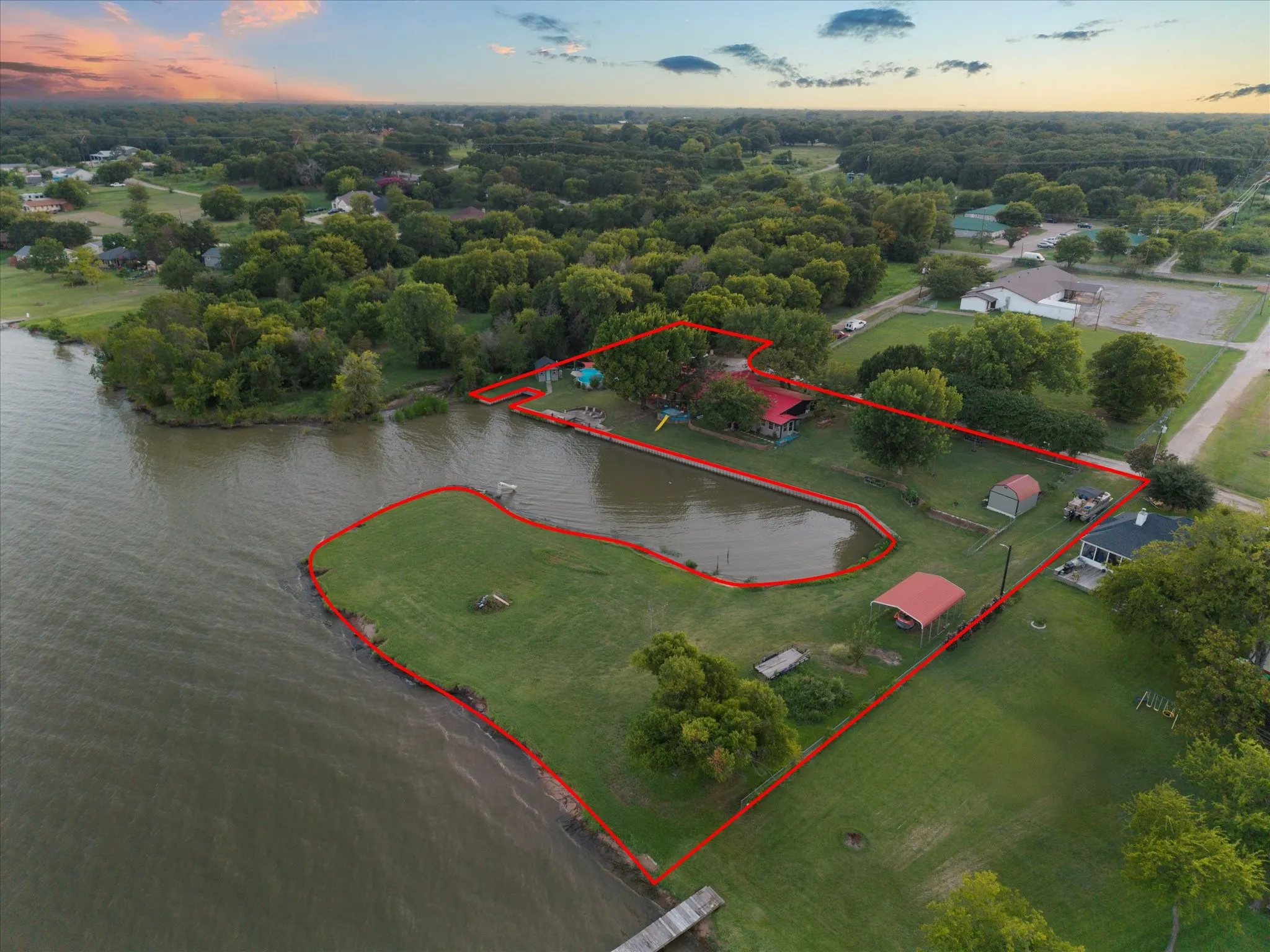 Waterfront property with a private pond, expansive grassy areas, and mature trees