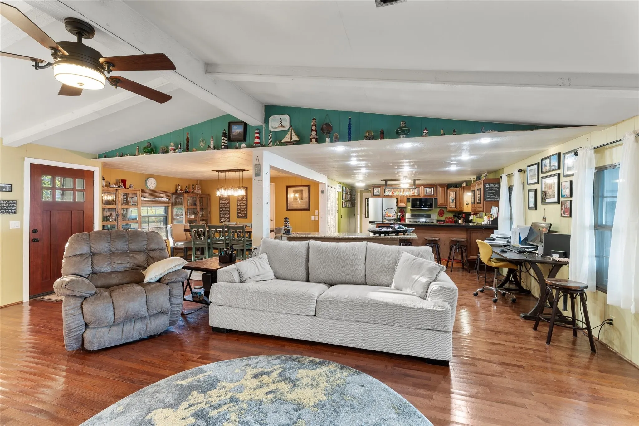 Vaulted ceiling with exposed beams, wood-finish flooring, recessed lighting, and kitchen area with built-in cabinetry