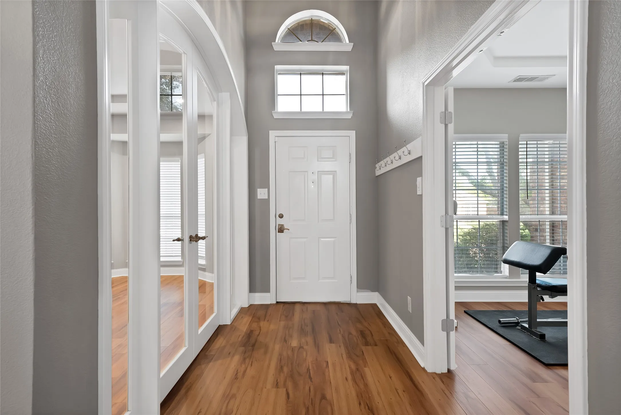 Wood-finish flooring, white trim throughout, and transom window above the entry door