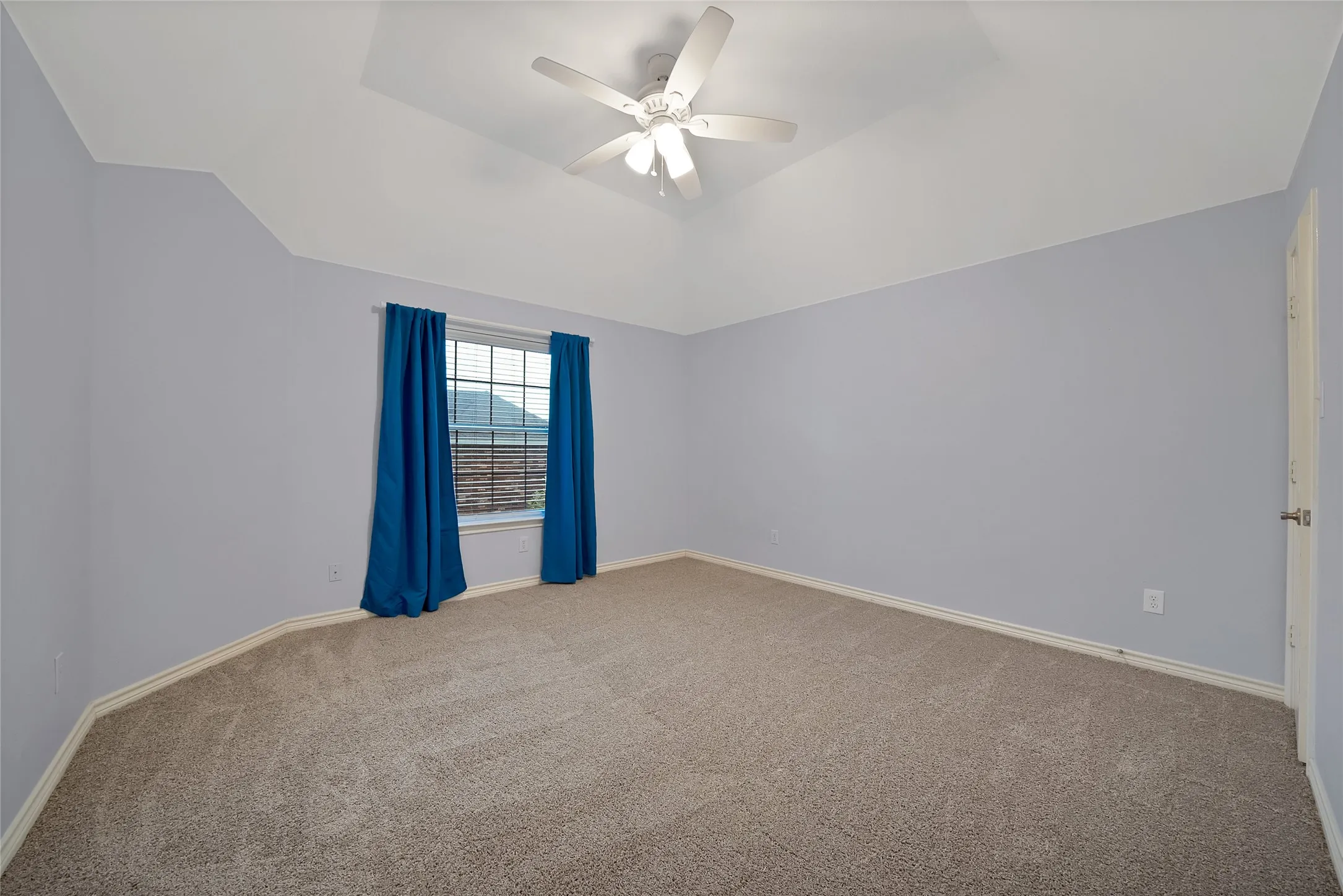 Vaulted ceiling, ceiling fan, carpet flooring, window with grilles, and light-toned walls