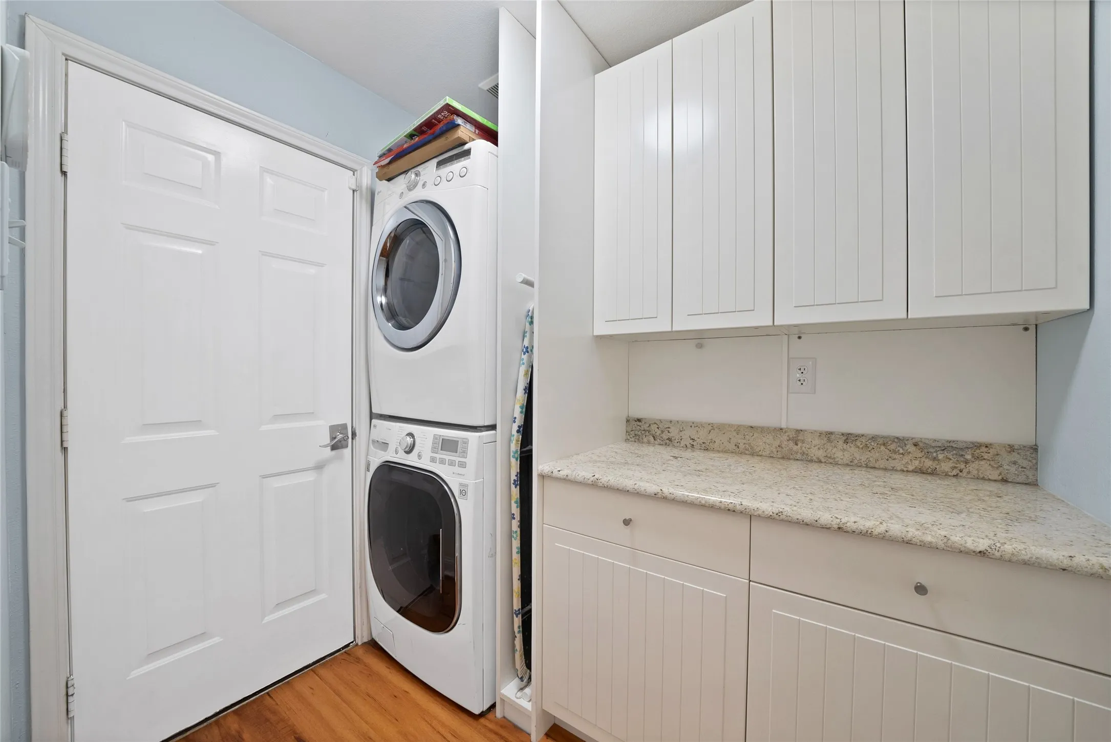White cabinetry with beadboard detailing, light-toned countertop, and wood-finish flooring