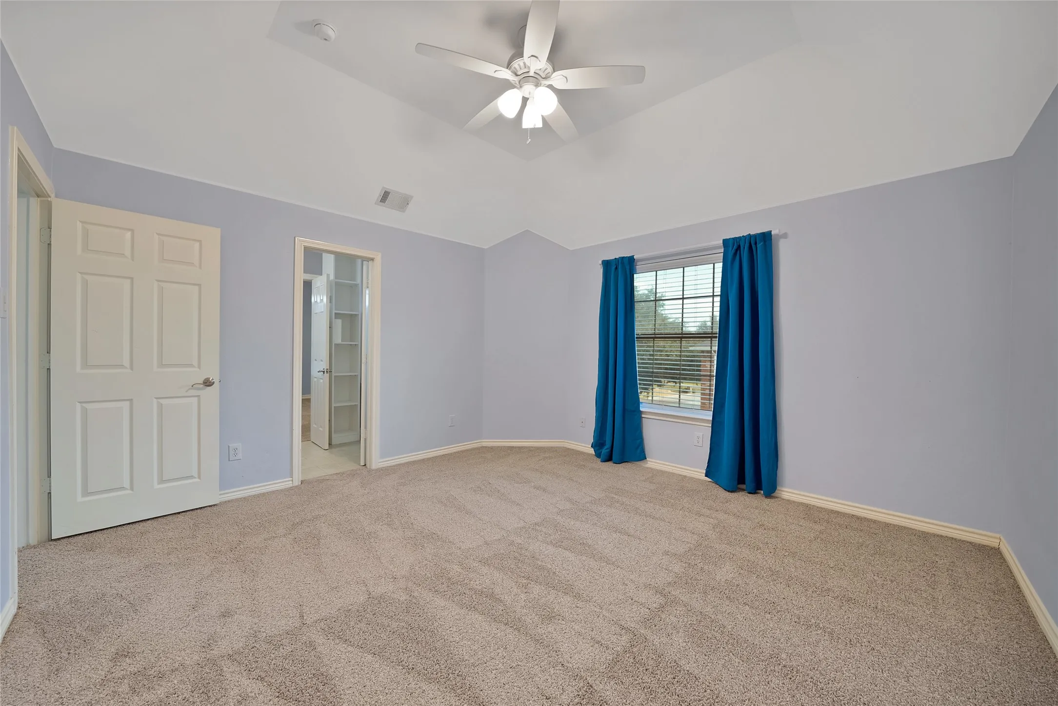 Carpeted room with a vaulted ceiling, a ceiling fan, and a window with blinds