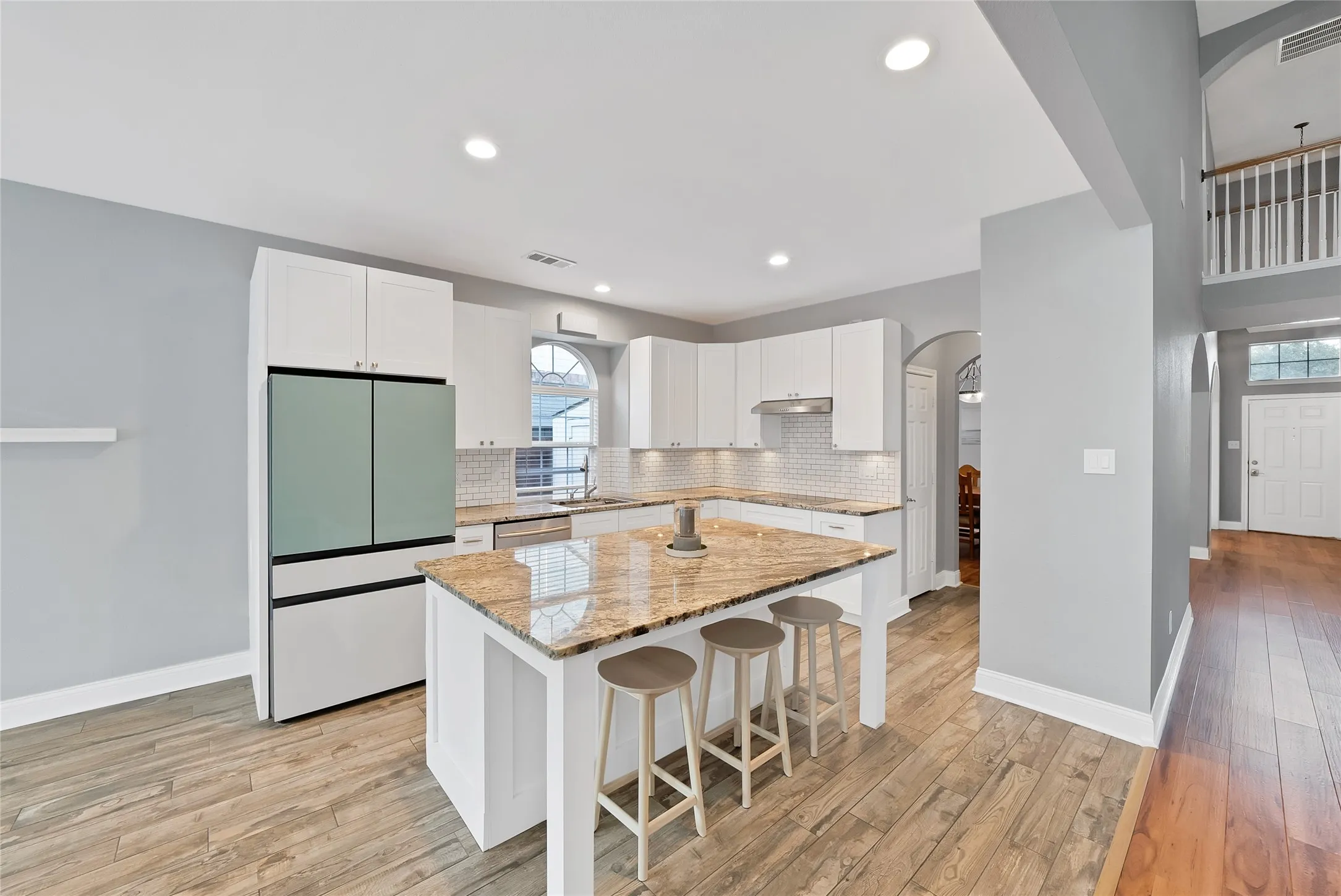Kitchen island with a granite countertop, white cabinetry, and recessed lighting
