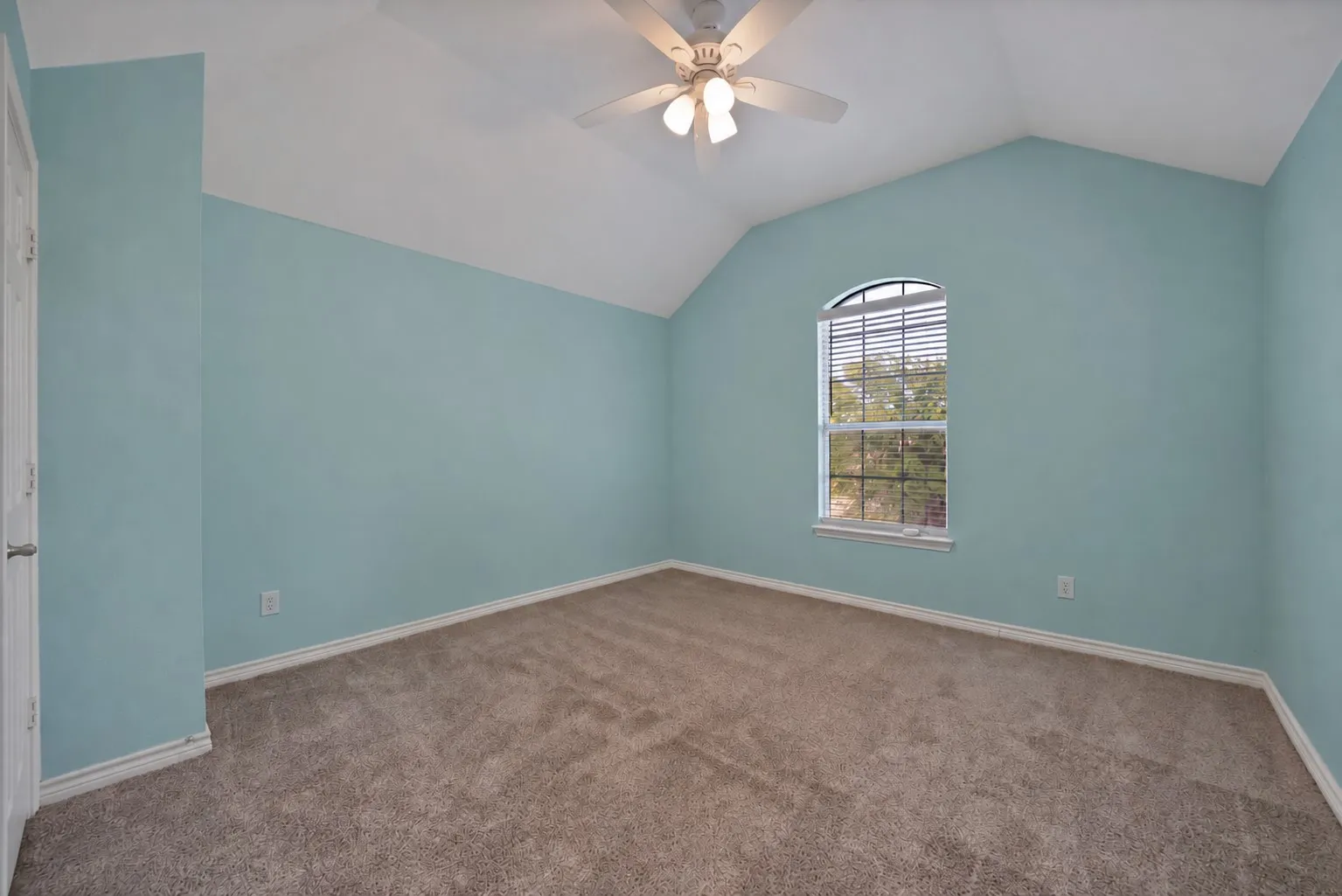 Vaulted ceiling with an arched window, ceiling fan, and carpeted flooring