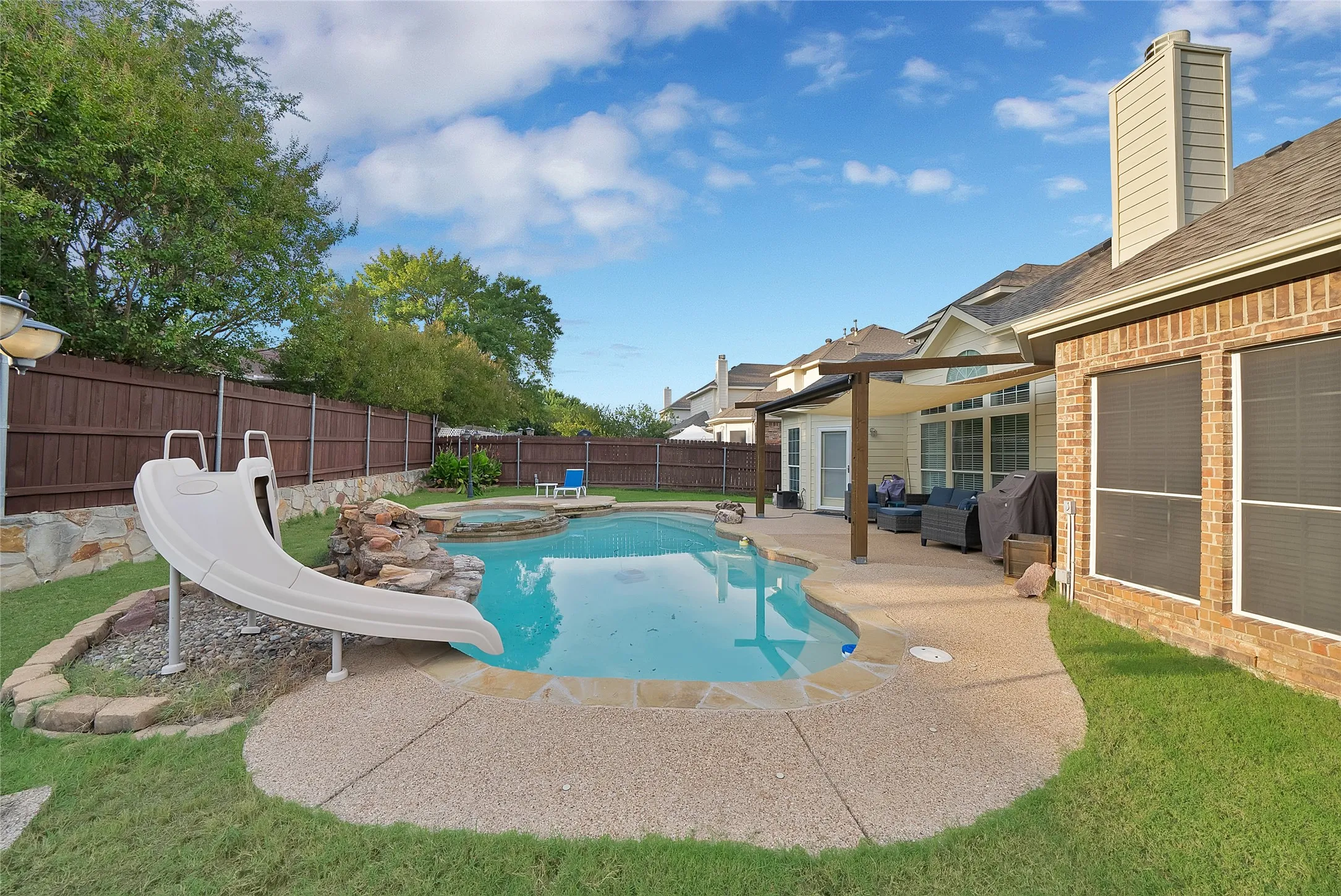 Backyard oasis featuring a swimming pool, integrated spa, and an attached patio with an overhead pergola