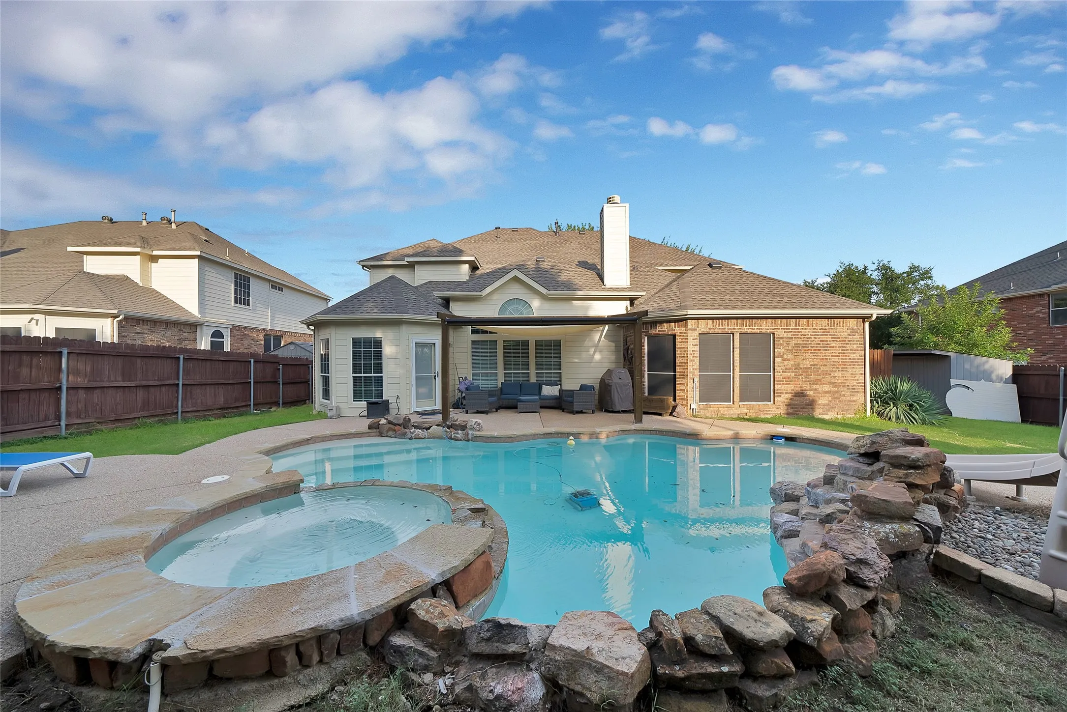 Outdoor swimming pool with integrated spa and rock-lined landscaping