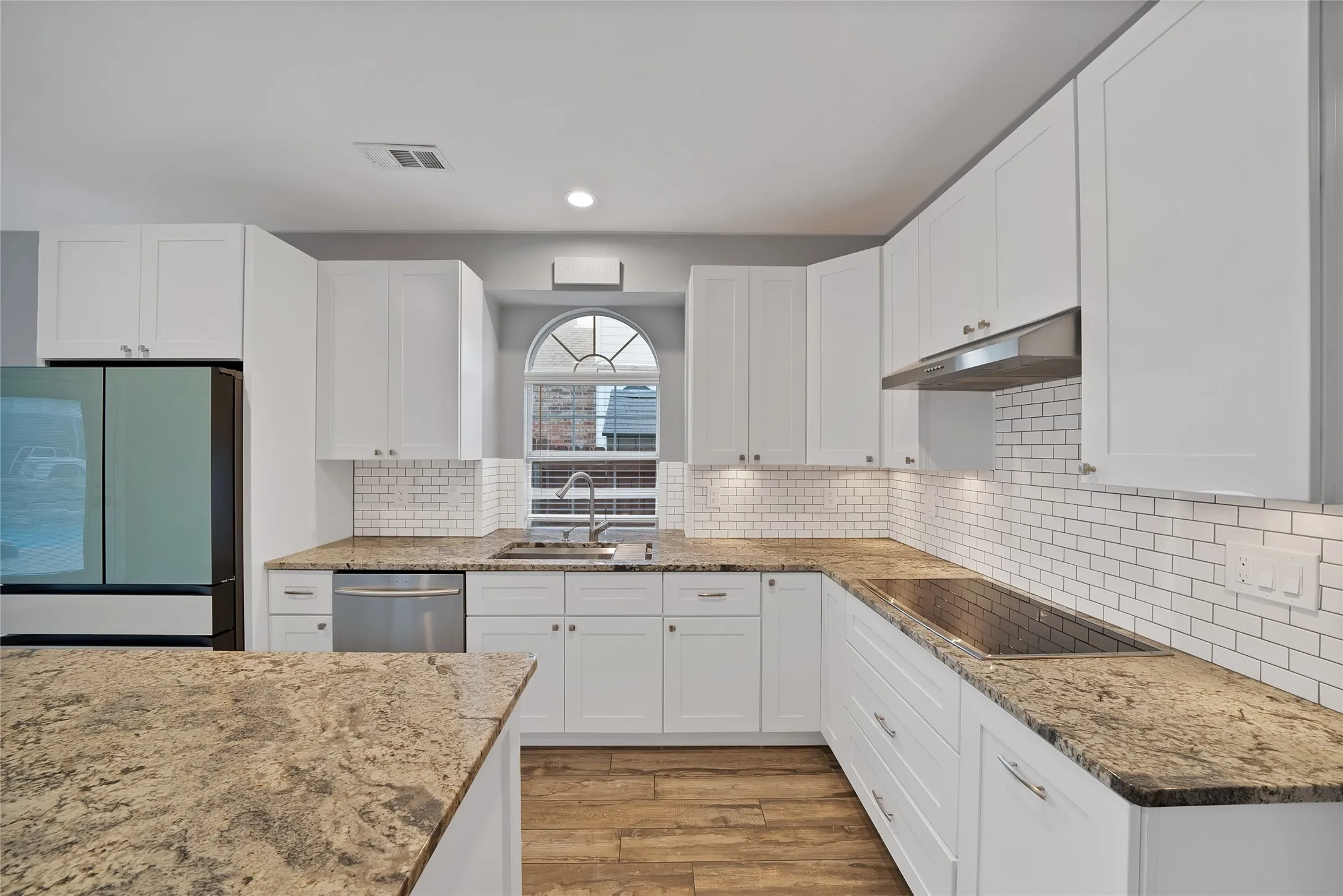 White cabinetry with stainless steel appliances, speckled stone countertops, and a subway tile backsplash