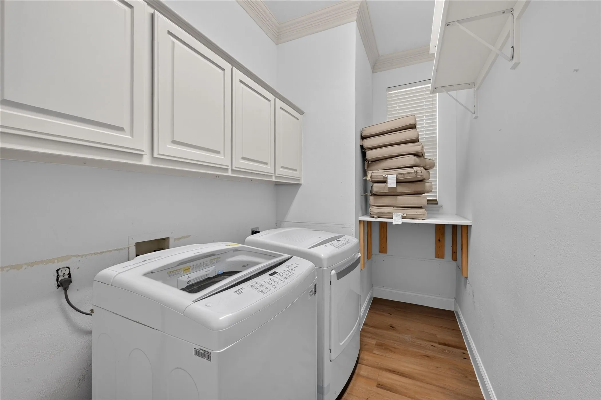 White shaker-style cabinetry, wood-finish flooring, a window with blinds, and a built-in folding shelf