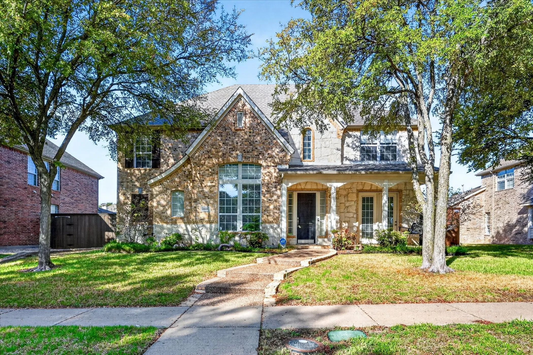 Stone and brick exterior with a pitched roof, featuring a covered front porch with arched openings and columns