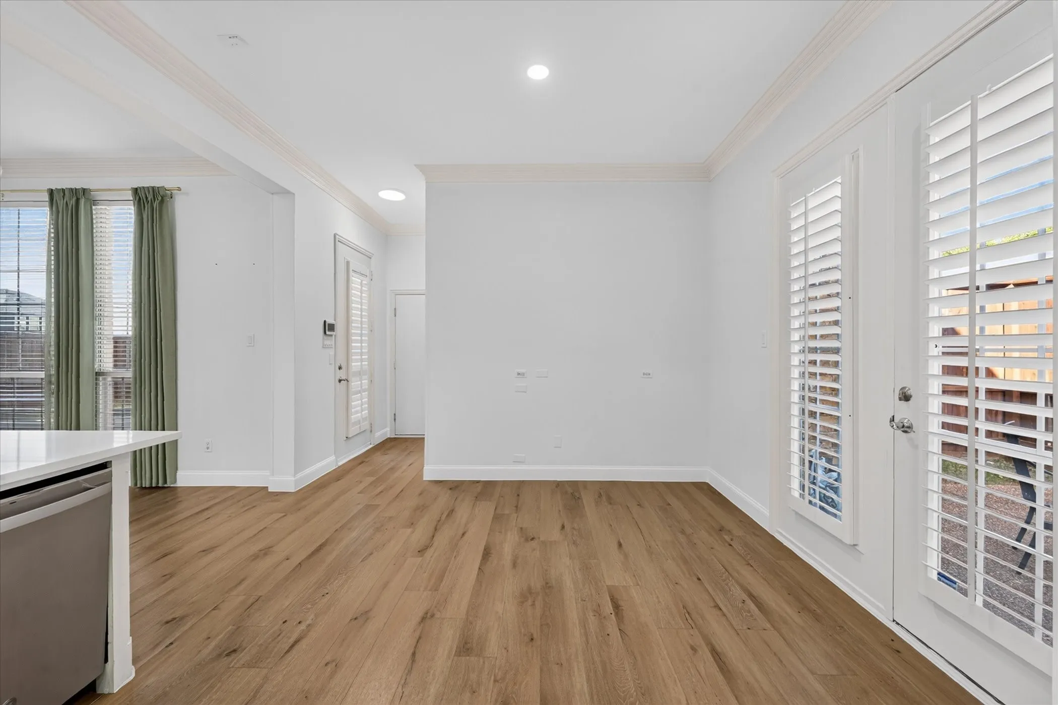 Wood-finish flooring, recessed lighting, crown molding, double French doors with plantation shutters, and a built-in kitchen appliance