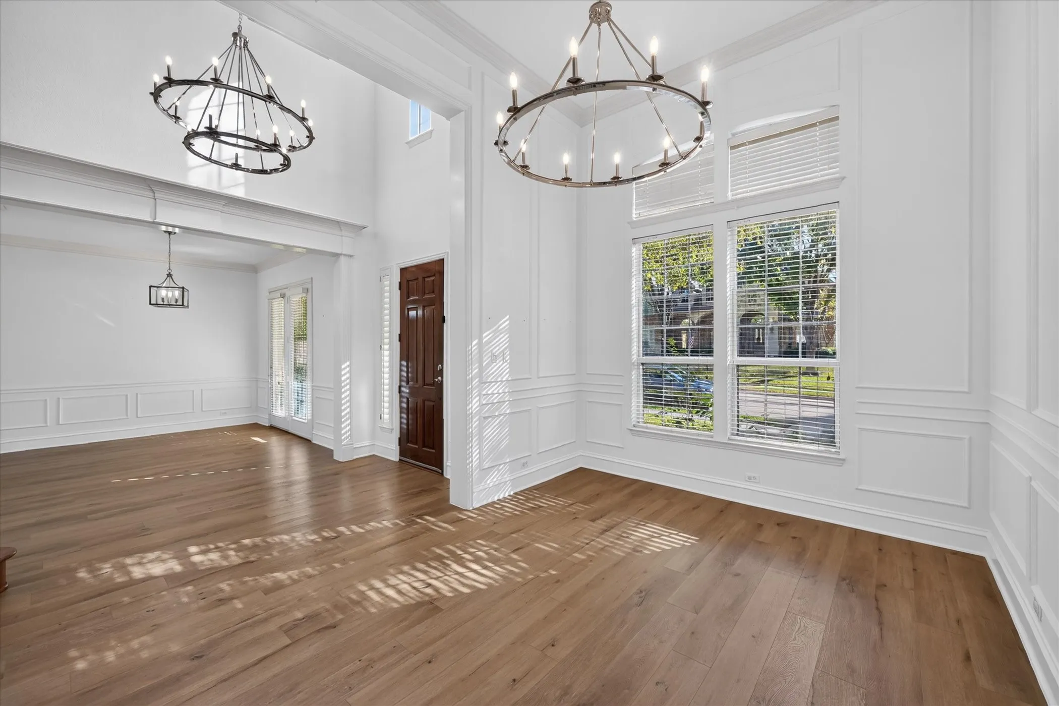 Hardwood flooring, double-height ceilings, decorative wainscoting, and a prominent chandelier