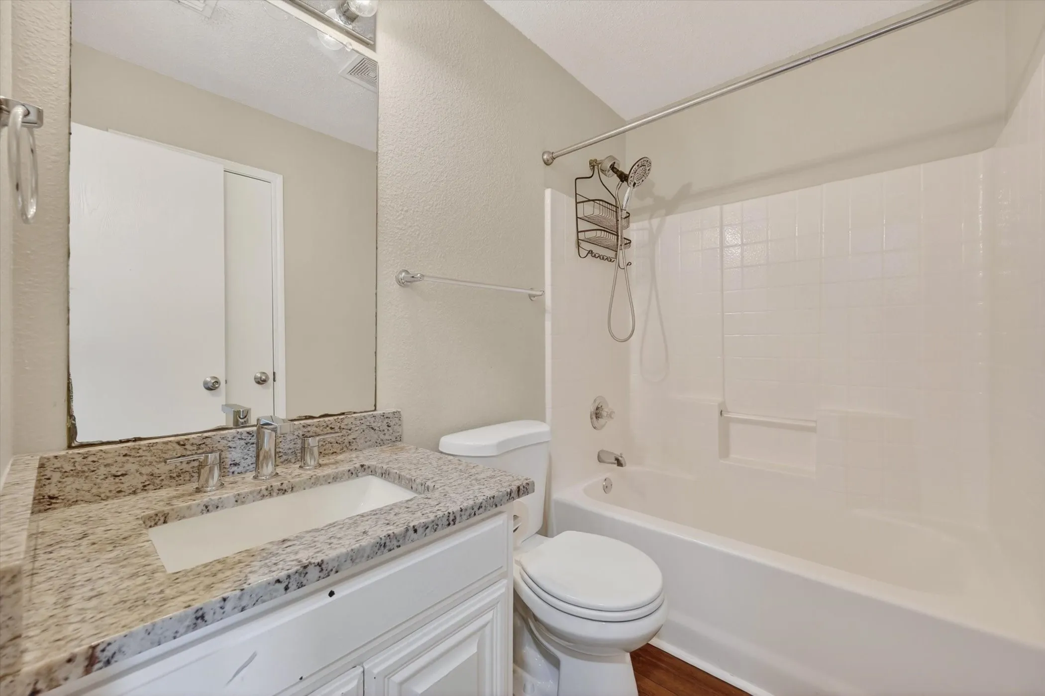 Bathroom featuring a white vanity with a light-toned countertop, an undermount sink, and a combination shower/tub with white subway-style tiling