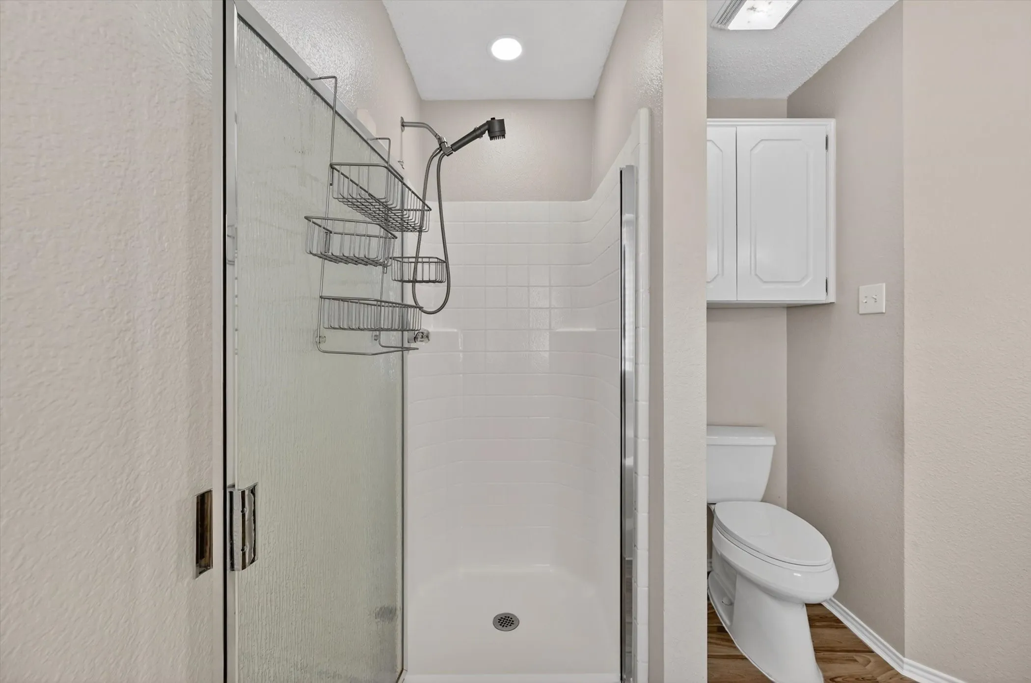 Glass-enclosed shower with white subway tile surround and a handheld showerhead