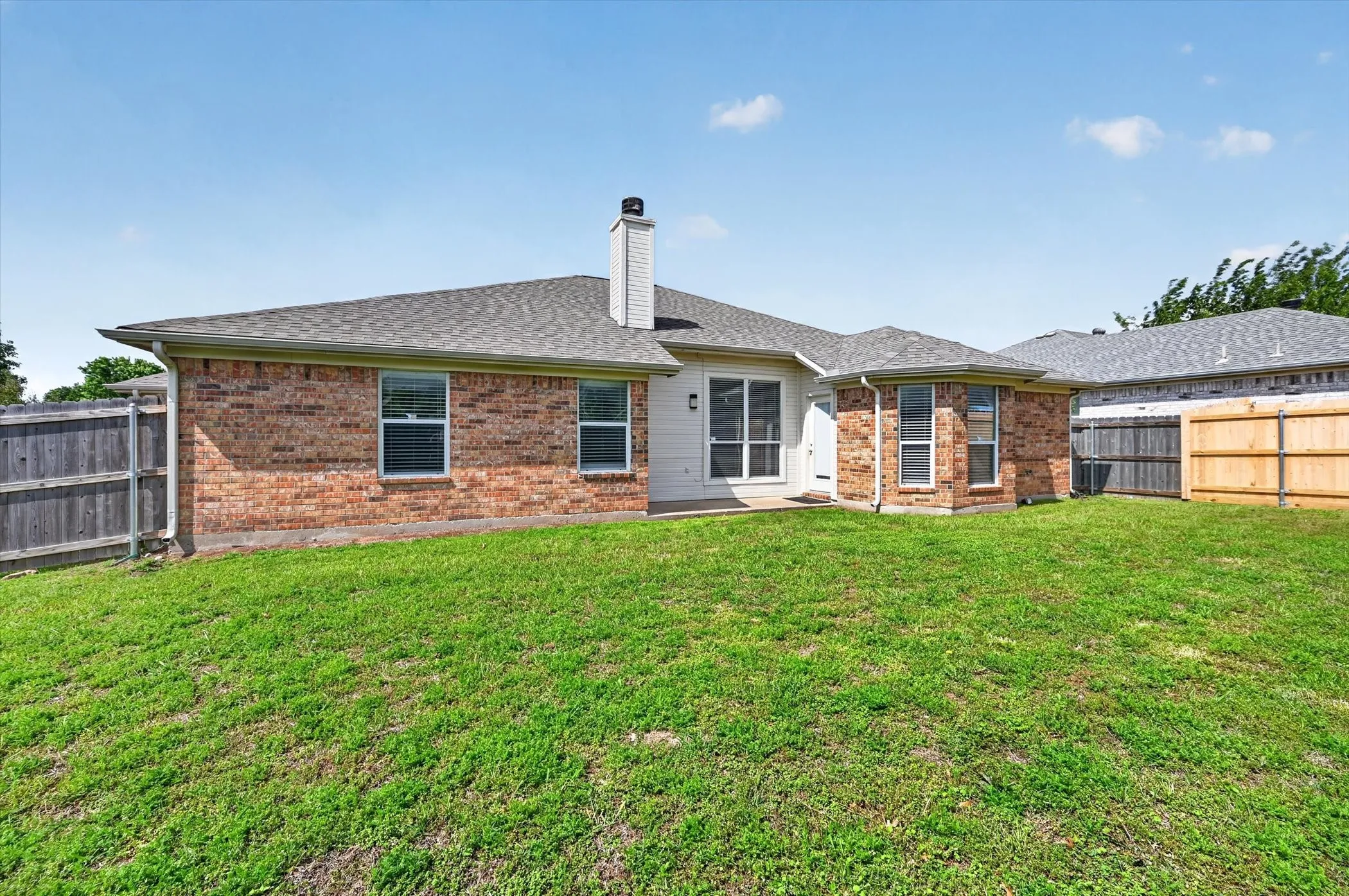 Expansive grassy yard with brick exterior, white siding, and a gabled roof