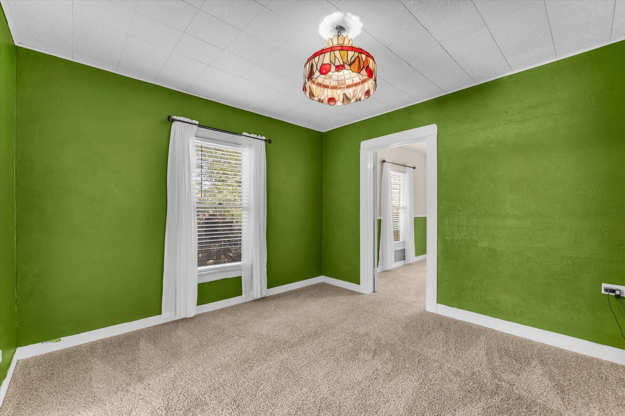 Carpeted room with a textured ceiling, a stained-glass light fixture, and a window with blinds