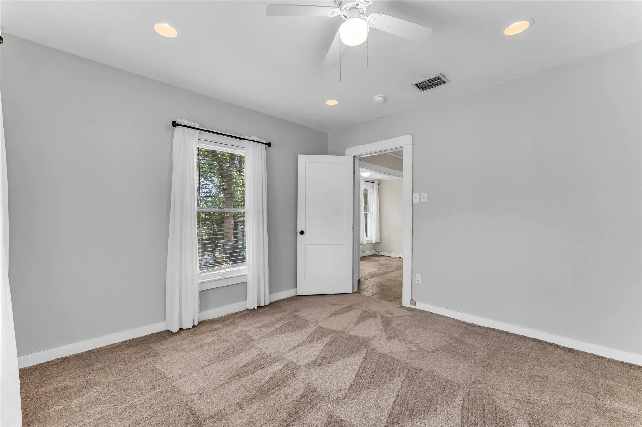 Recessed ceiling lighting, ceiling fan, carpet flooring, window with blinds, and white interior door