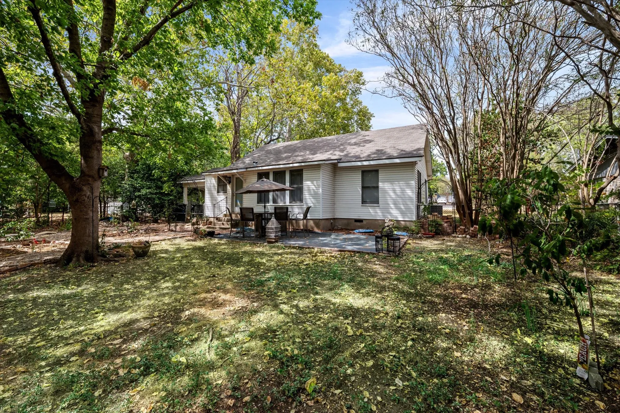 Expansive backyard with a manicured lawn, mature trees, and a paver patio