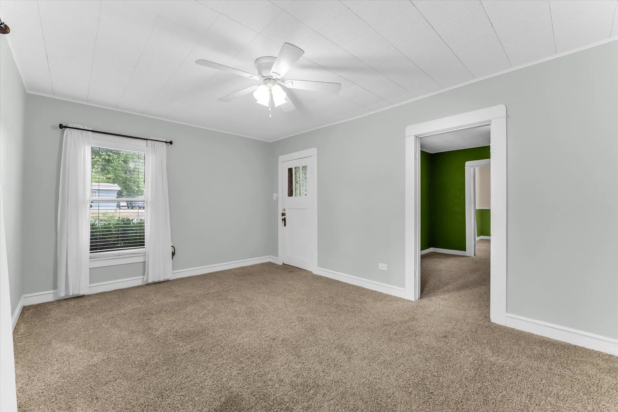 Carpeted room with light gray walls, a white ceiling fan, and a paneled ceiling