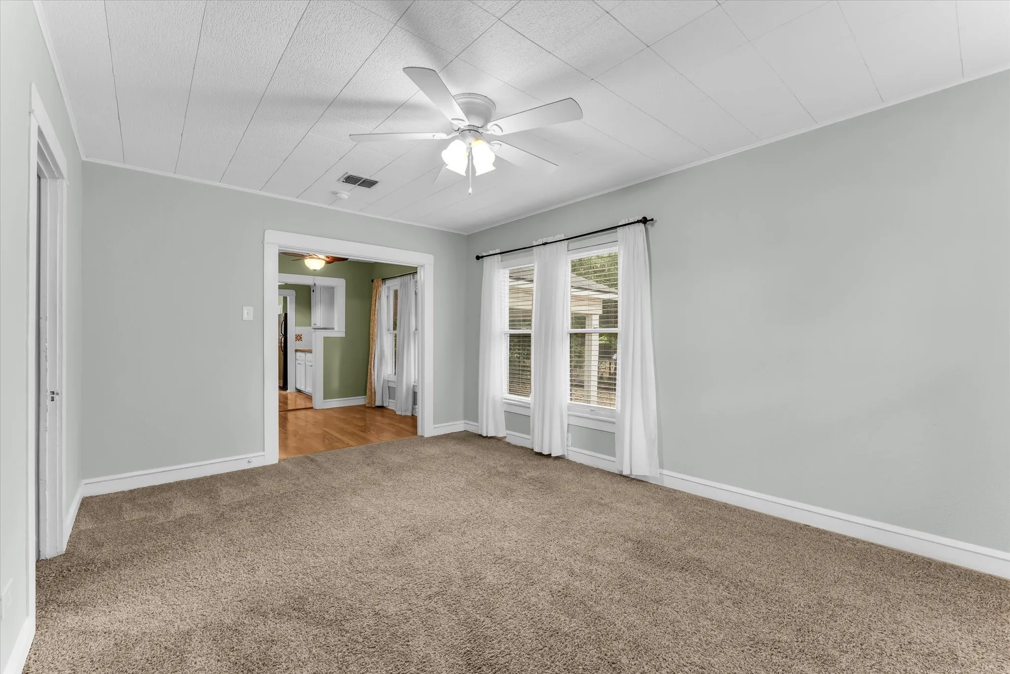 Recessed ceiling with an overhead fan, dual windows, and carpeted flooring