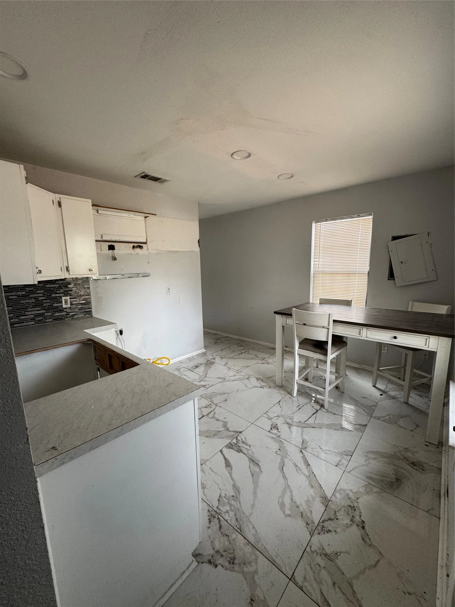 Kitchenette featuring white cabinetry, grey subway tile backsplash, and light-toned countertops