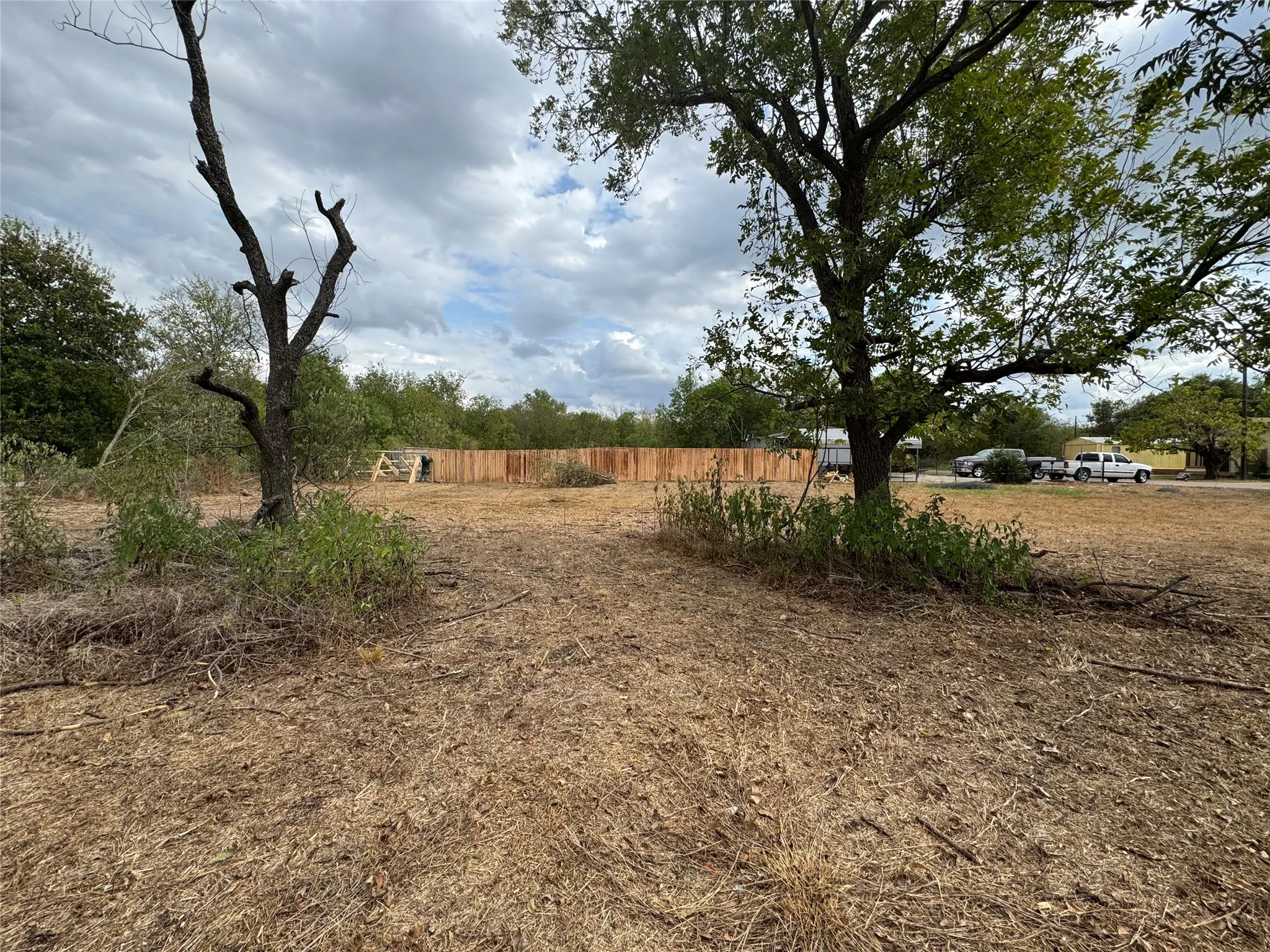 Cleared lot featuring natural landscaping and a wood privacy fence