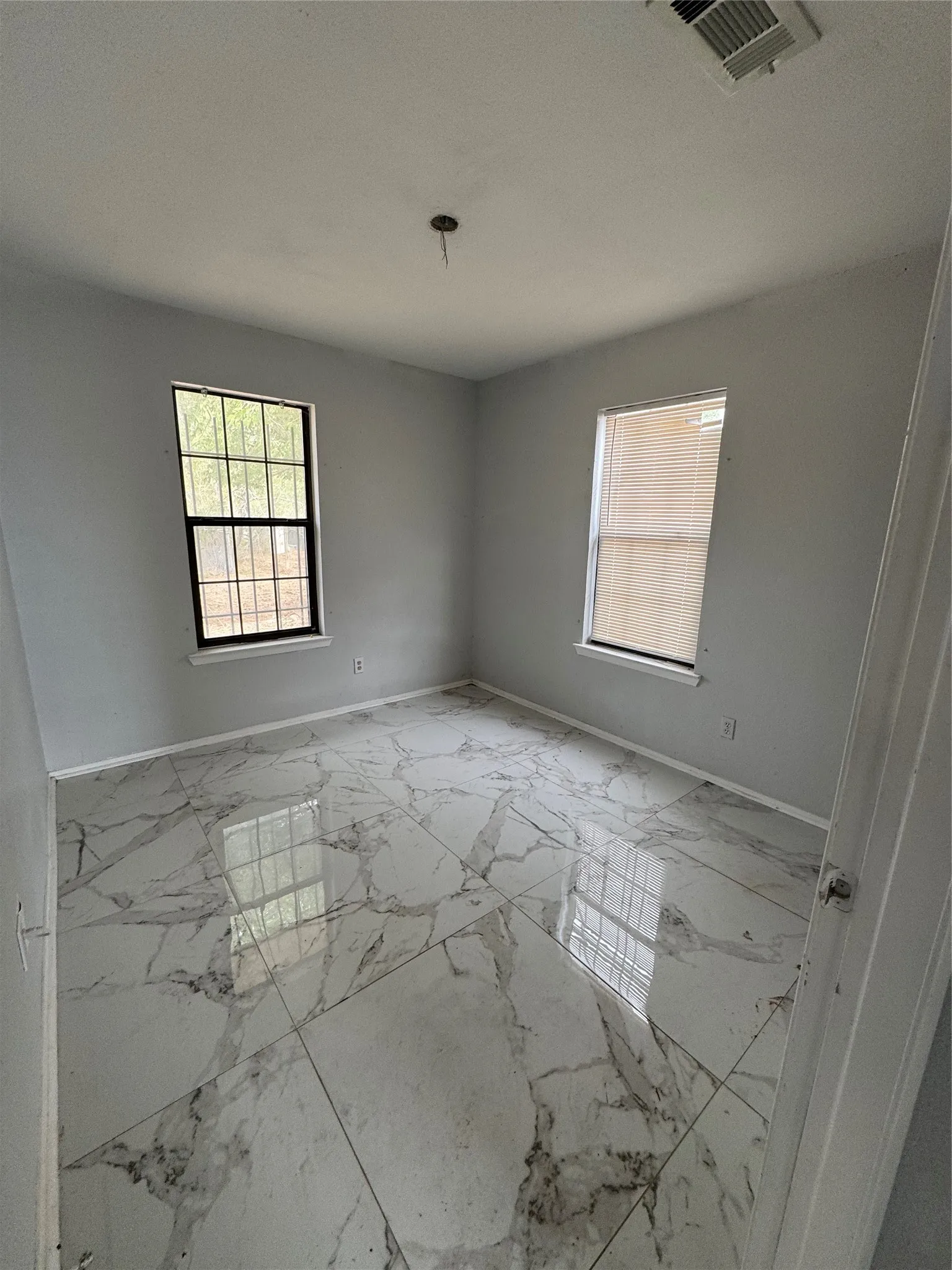 Polished tile flooring with veining, two windows, and light gray walls