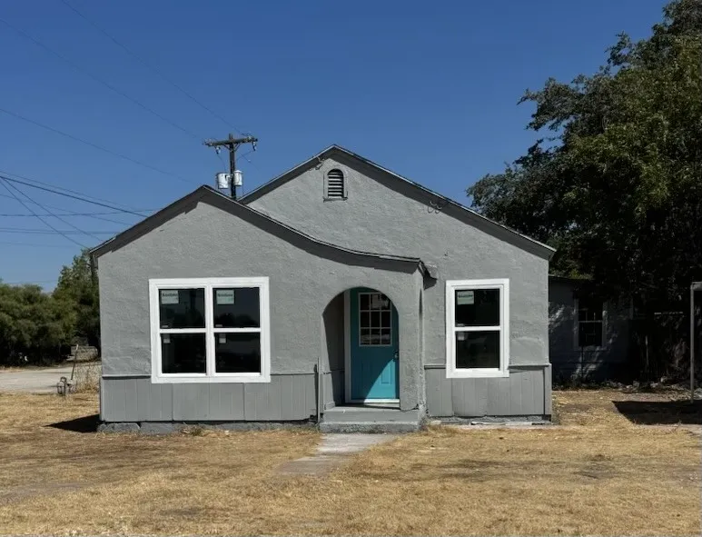 Stucco exterior with a gable roof, archway entry, and a vibrant turquoise front door