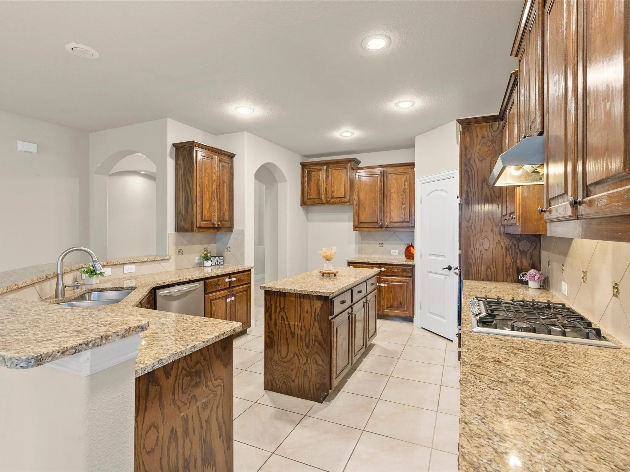 Kitchen featuring recessed lighting, a central island, wood cabinetry, stone countertops, and tile flooring