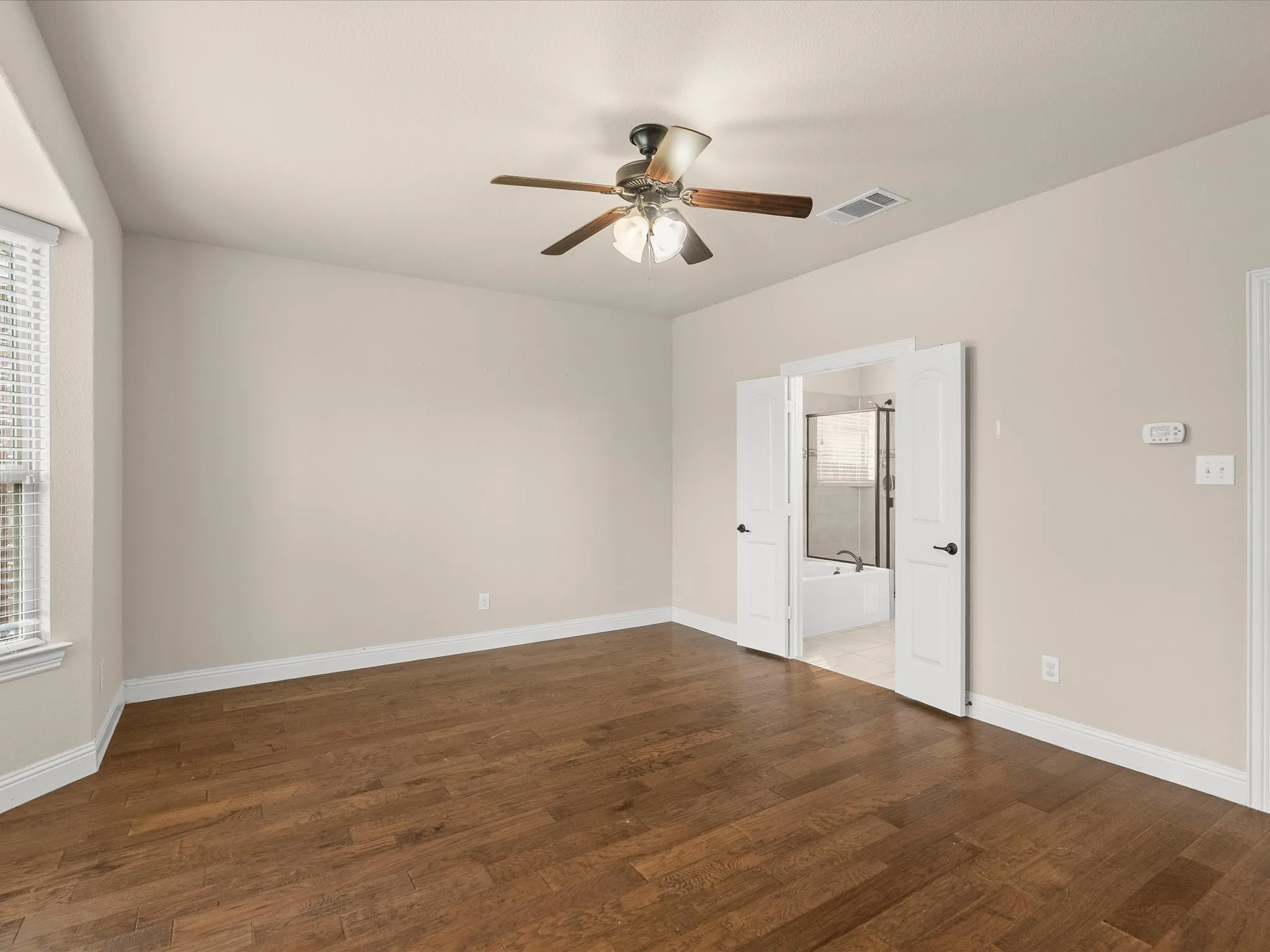 Wood-finish flooring, ceiling fan with integrated lighting, double entry doors, window with blinds, and white trim