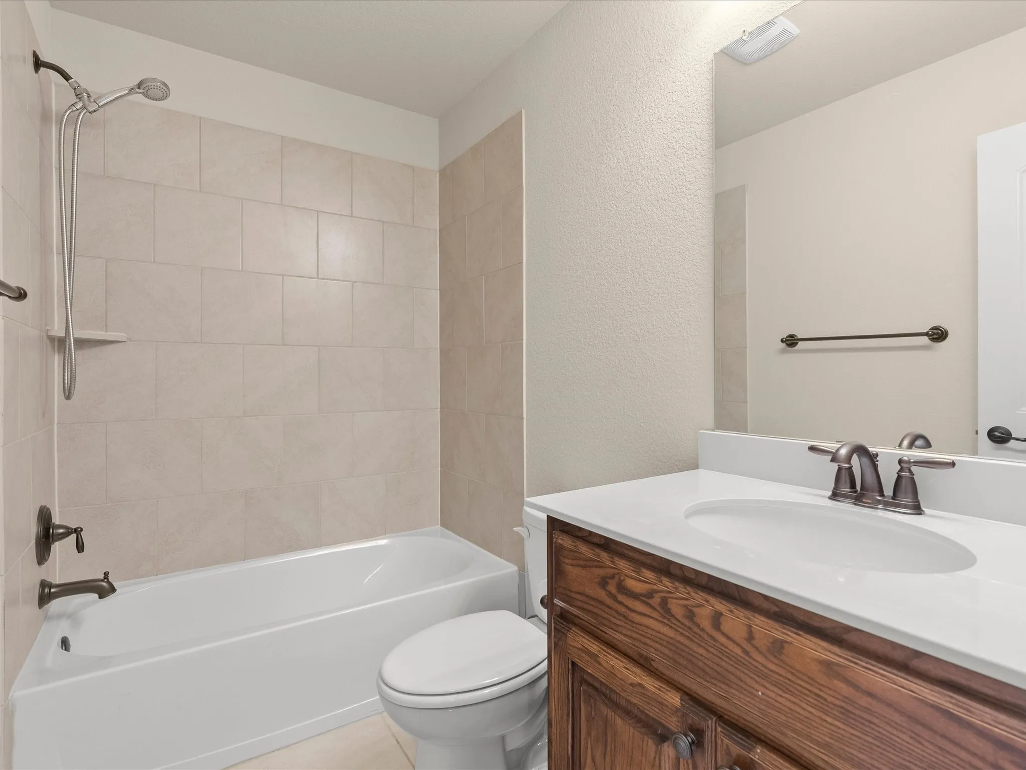 Spa-inspired bathroom featuring a wood-finish vanity with dual sinks, white quartz countertop, and oil-rubbed bronze faucetry
