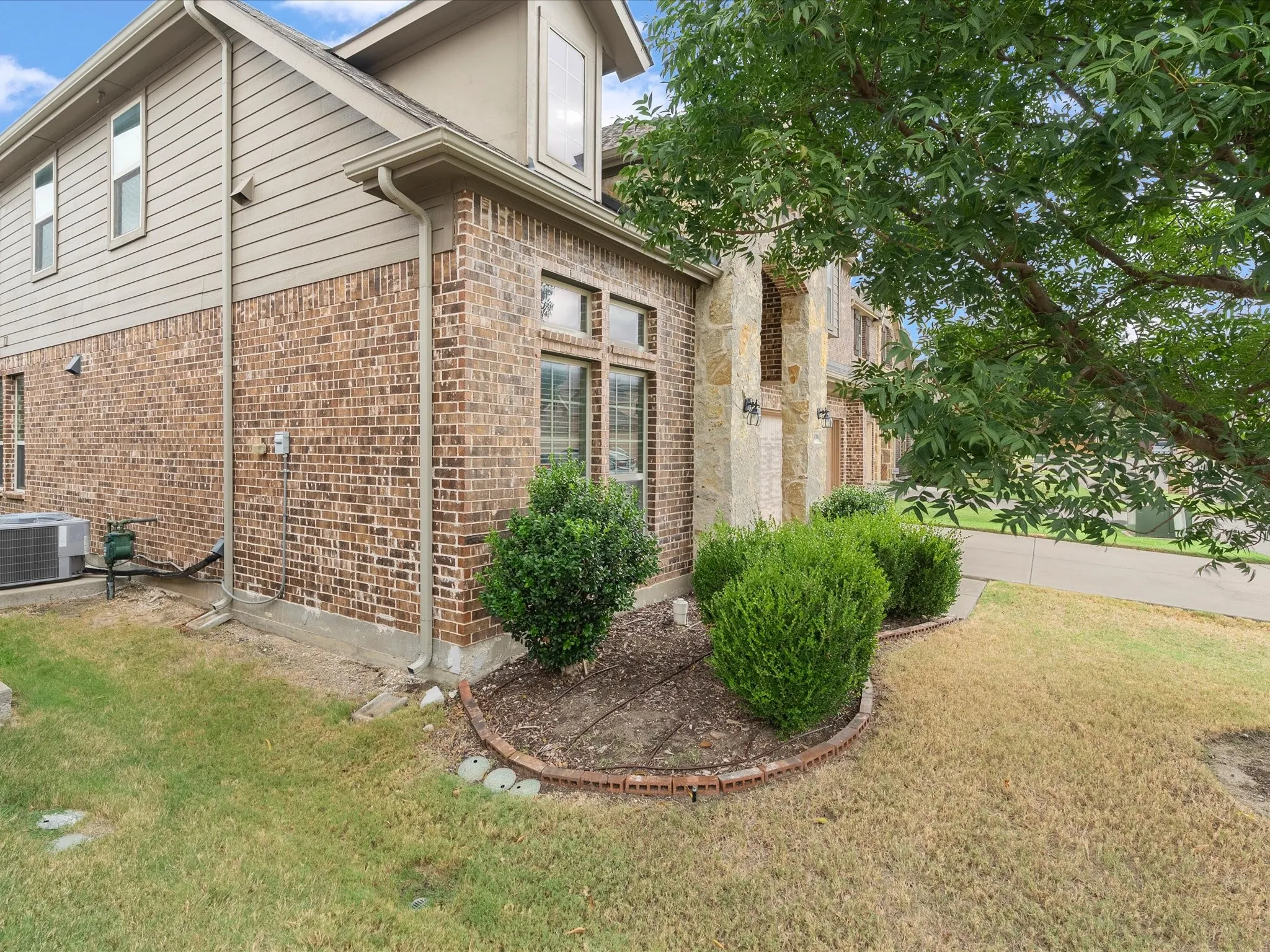 Brick and siding exterior with stone accents, dormer window, and established landscaping