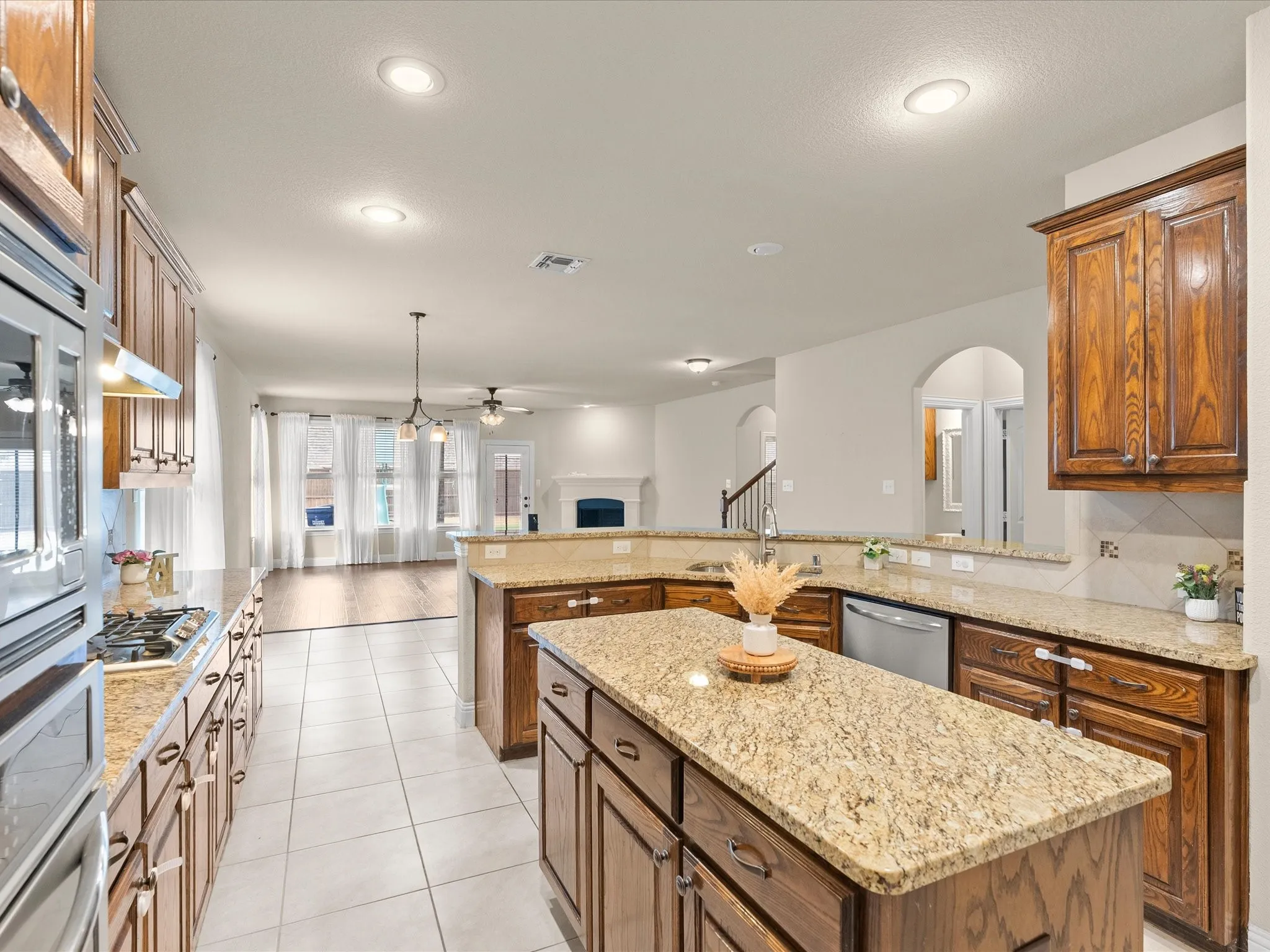 Kitchen featuring wood-finish cabinetry, granite countertops, a central island, and stainless steel appliances