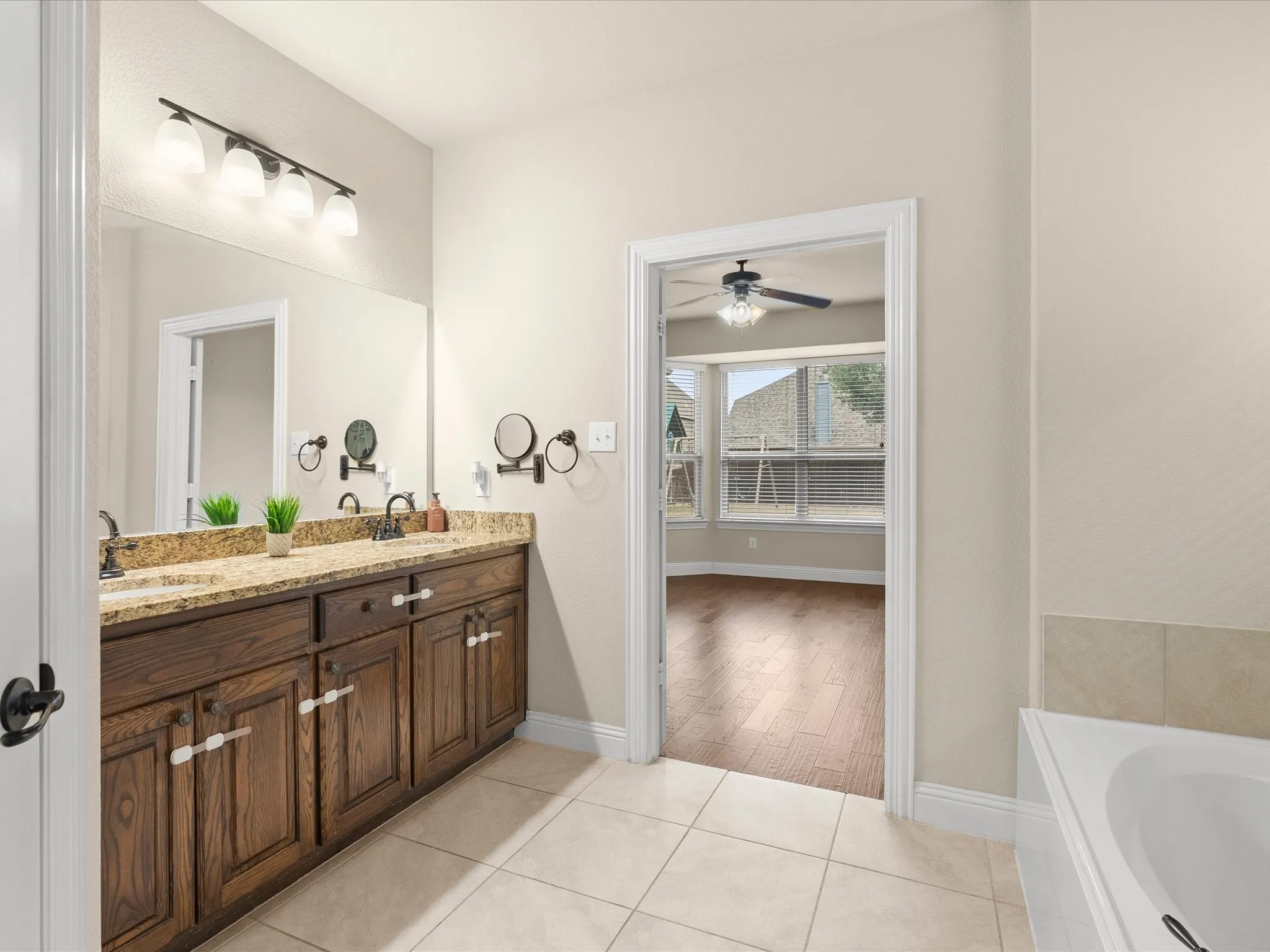 Double vanity with granite-style countertop, wood cabinetry, and dual sinks