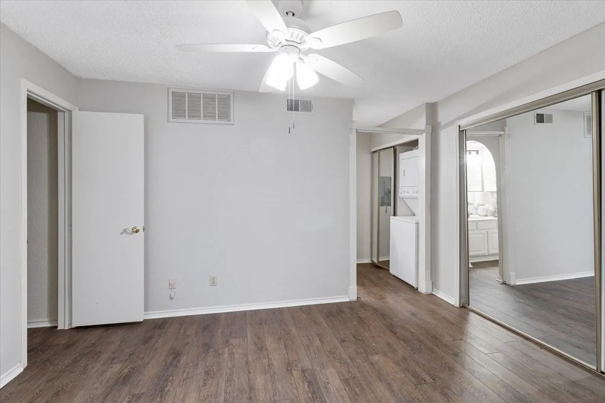 Wood-finish flooring, white ceiling fan, and mirrored closet doors