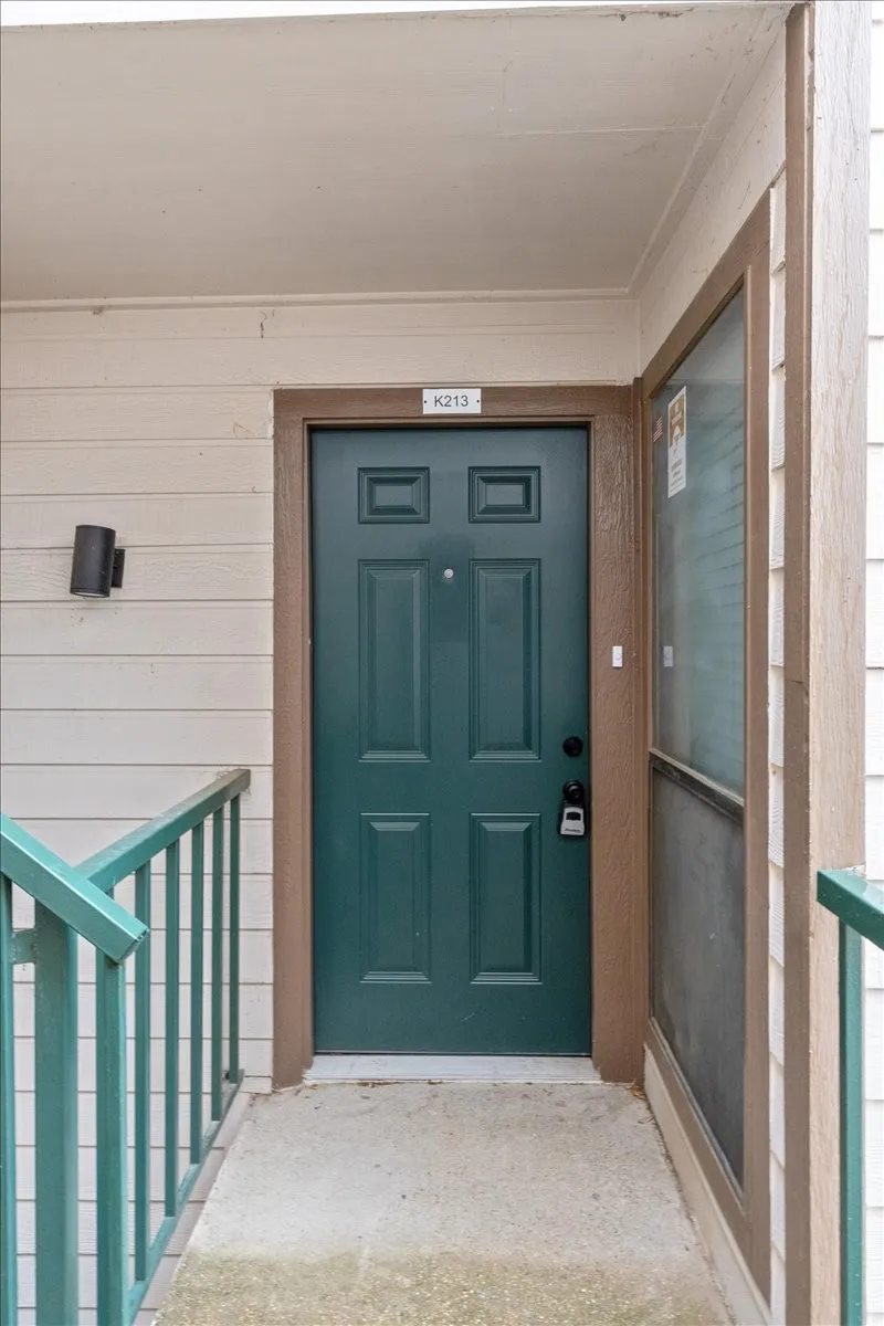 Entryway featuring a paneled door, exterior wall light fixture, and metal railings
