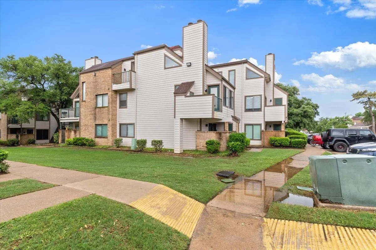 Multi-level exterior with brick and siding facade, featuring balconies, prominent chimneys, and mature landscaping