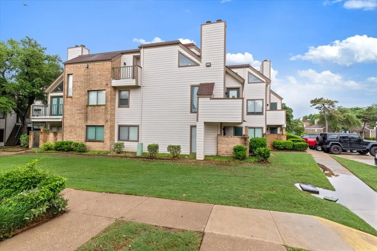 Multi-level facade featuring brick and siding, multiple balconies, and triangular window elements