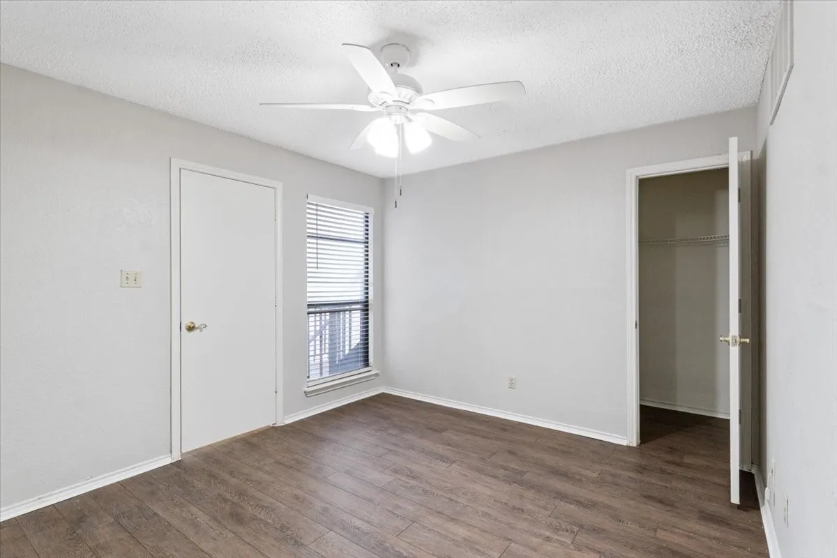Wood-finish flooring, white walls, and a ceiling fan with light fixture