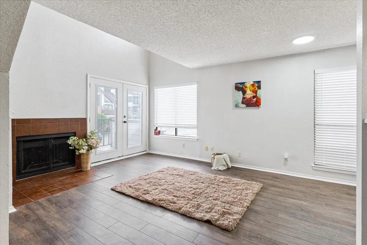 Vaulted ceiling with a skylight, wood-finish flooring, and a fireplace with a tile surround