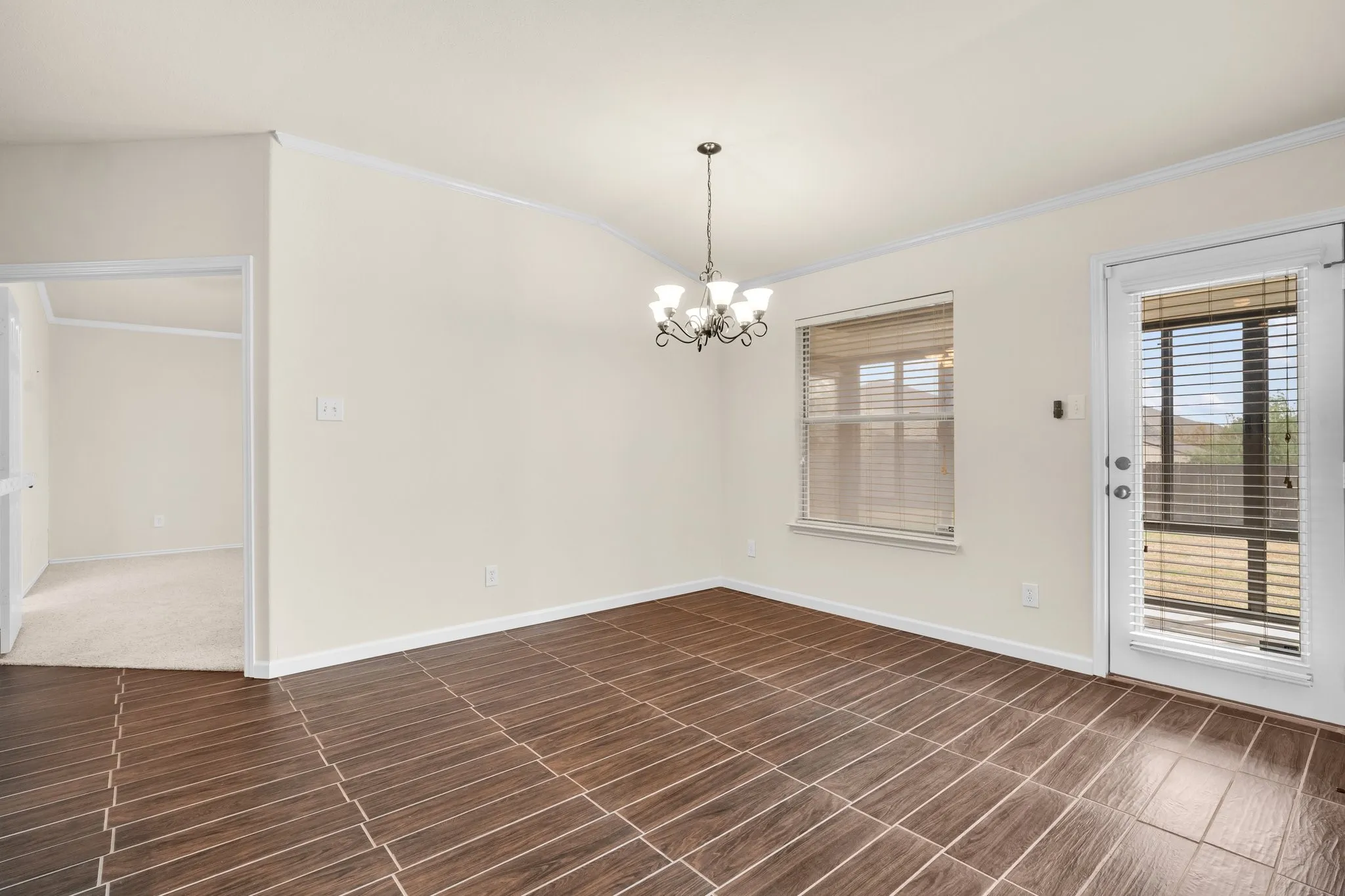Tile flooring, chandelier, window with blinds, and exterior door with integrated blinds