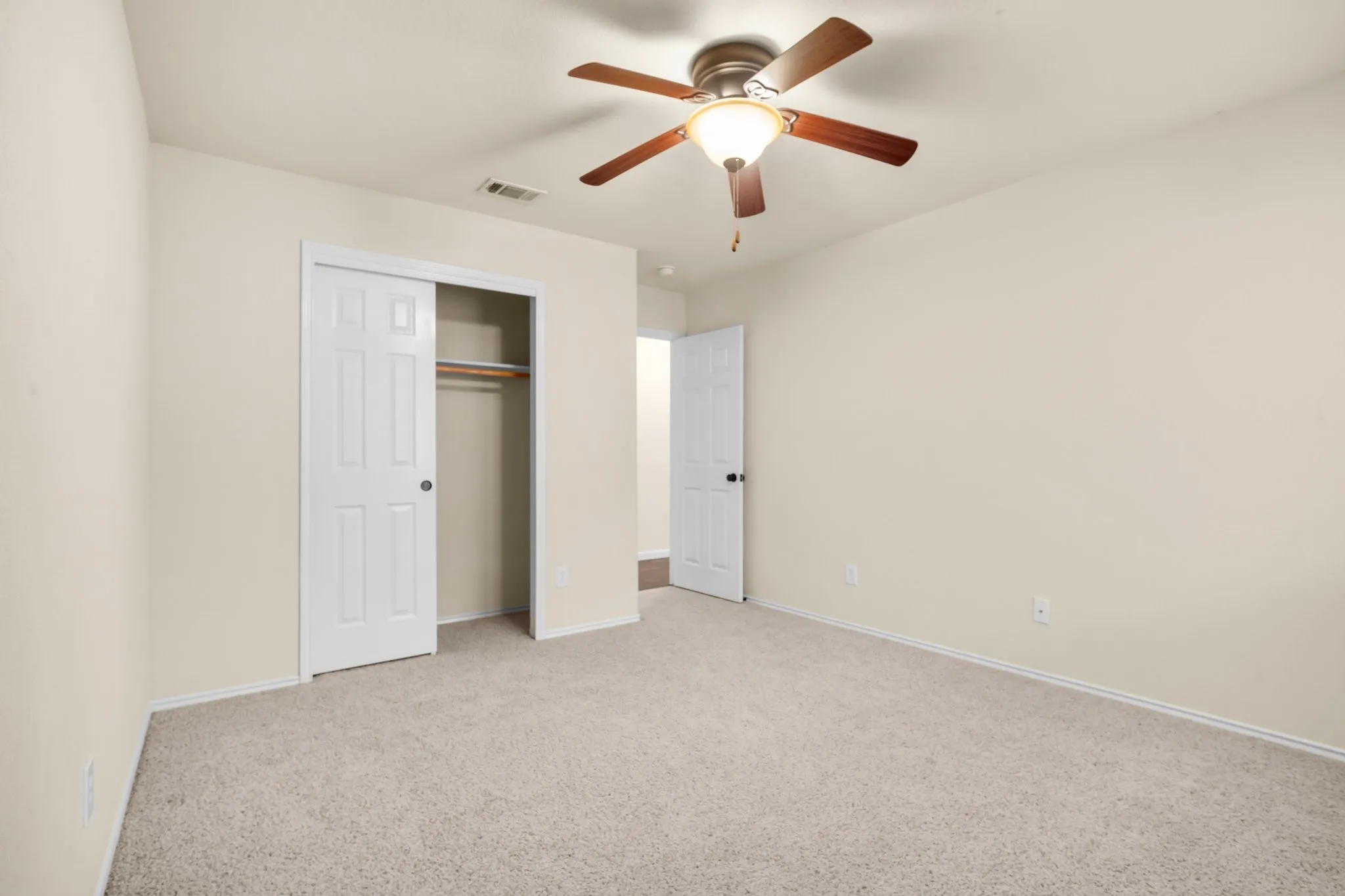 Wall-to-wall carpeting, overhead ceiling fan with lighting, and white paneled doors